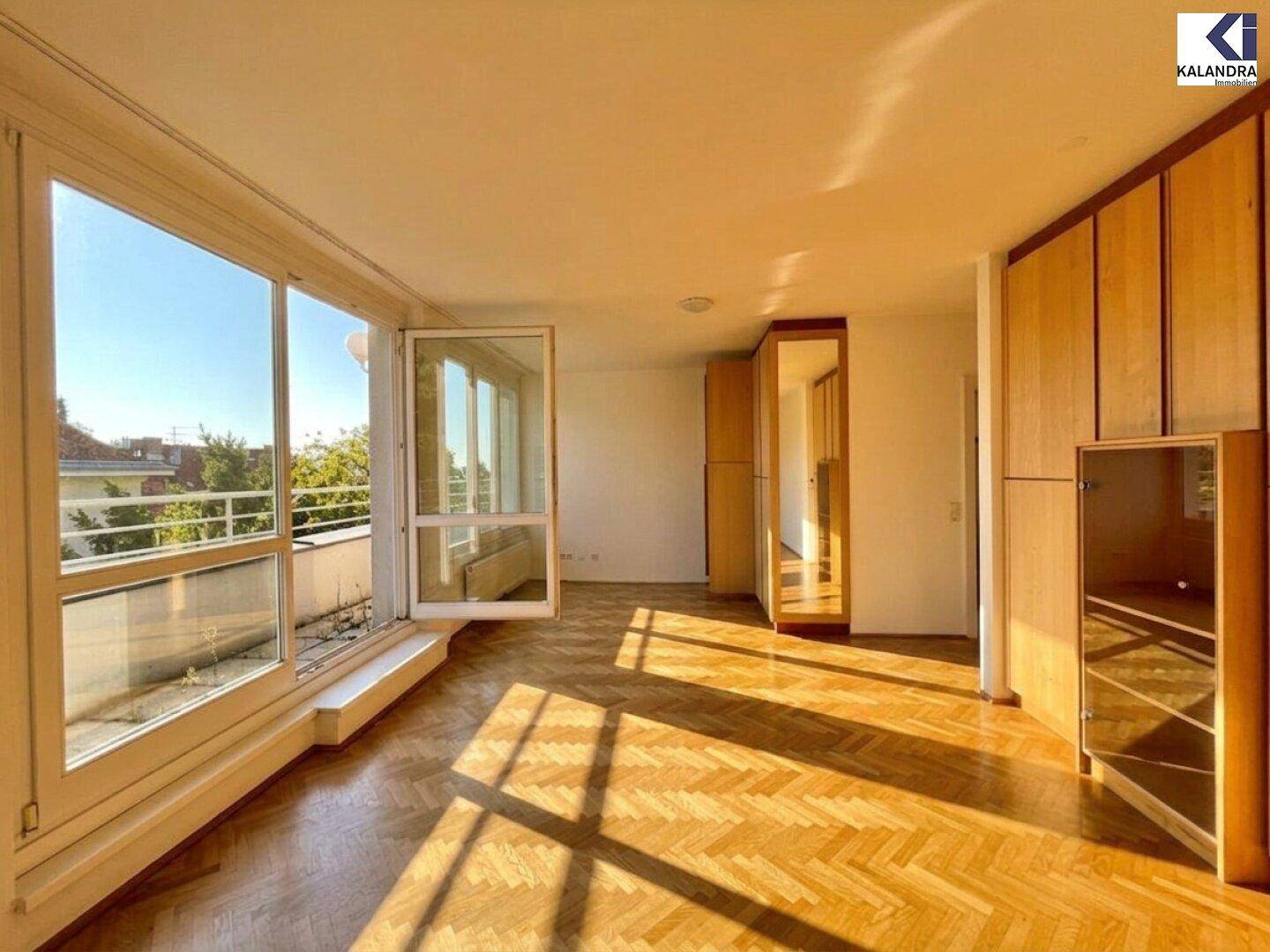 Geräumiges Wohnzimmer mit großen Fenstern, Einbauschränken und hellem Fischgrätparkett.