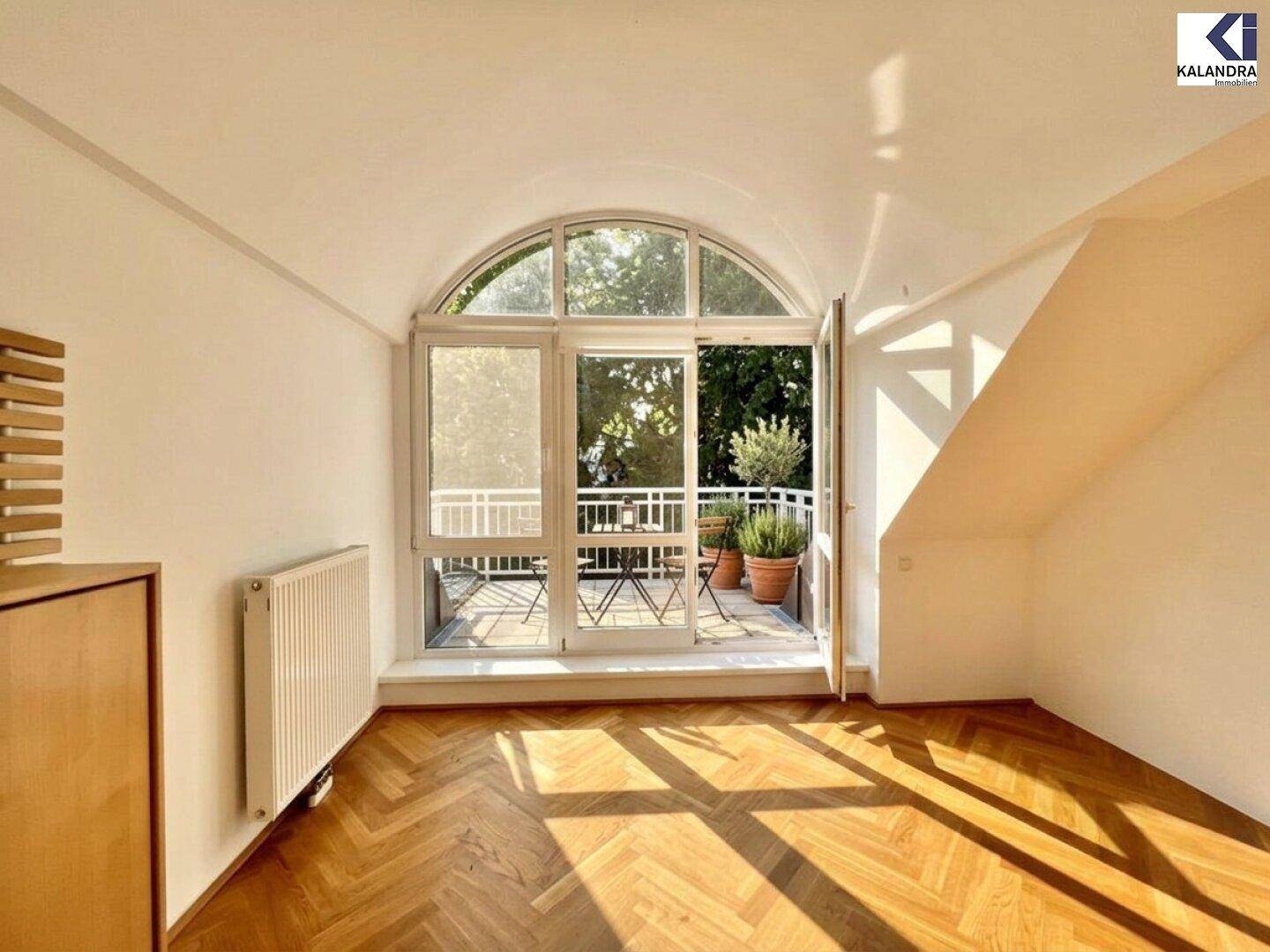 Heller Raum mit elegantem Rundbogenfenster und direktem Zugang zu einem sonnigen Balkon.