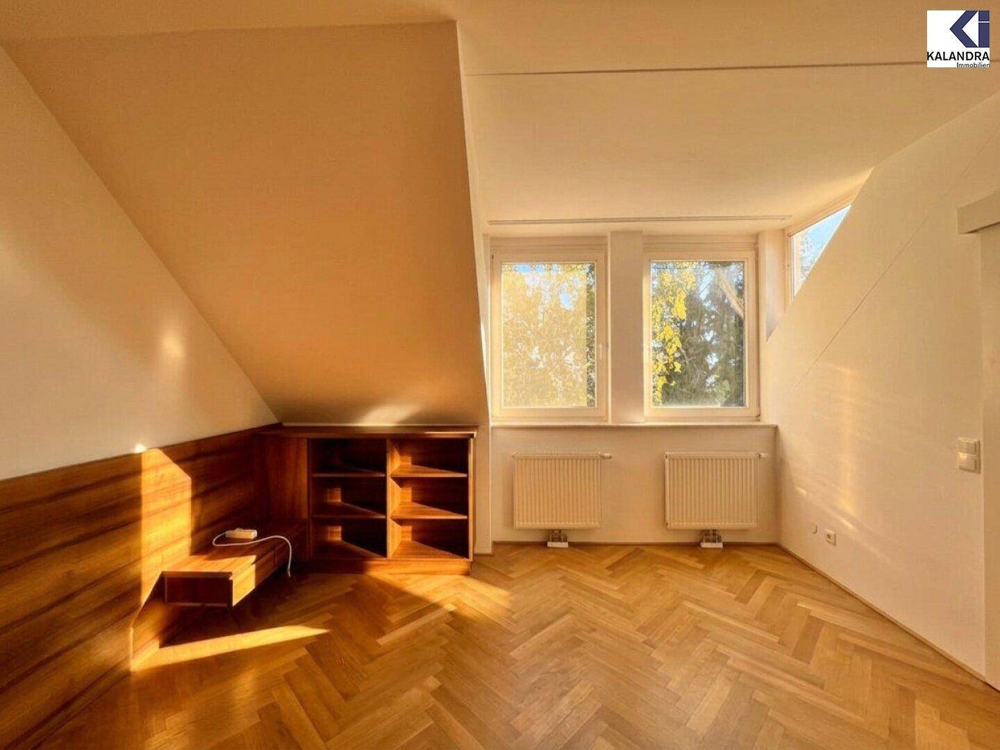 Gemütliches Schlafzimmer mit Dachschräge, Einbauregalen und hellem Parkettboden.