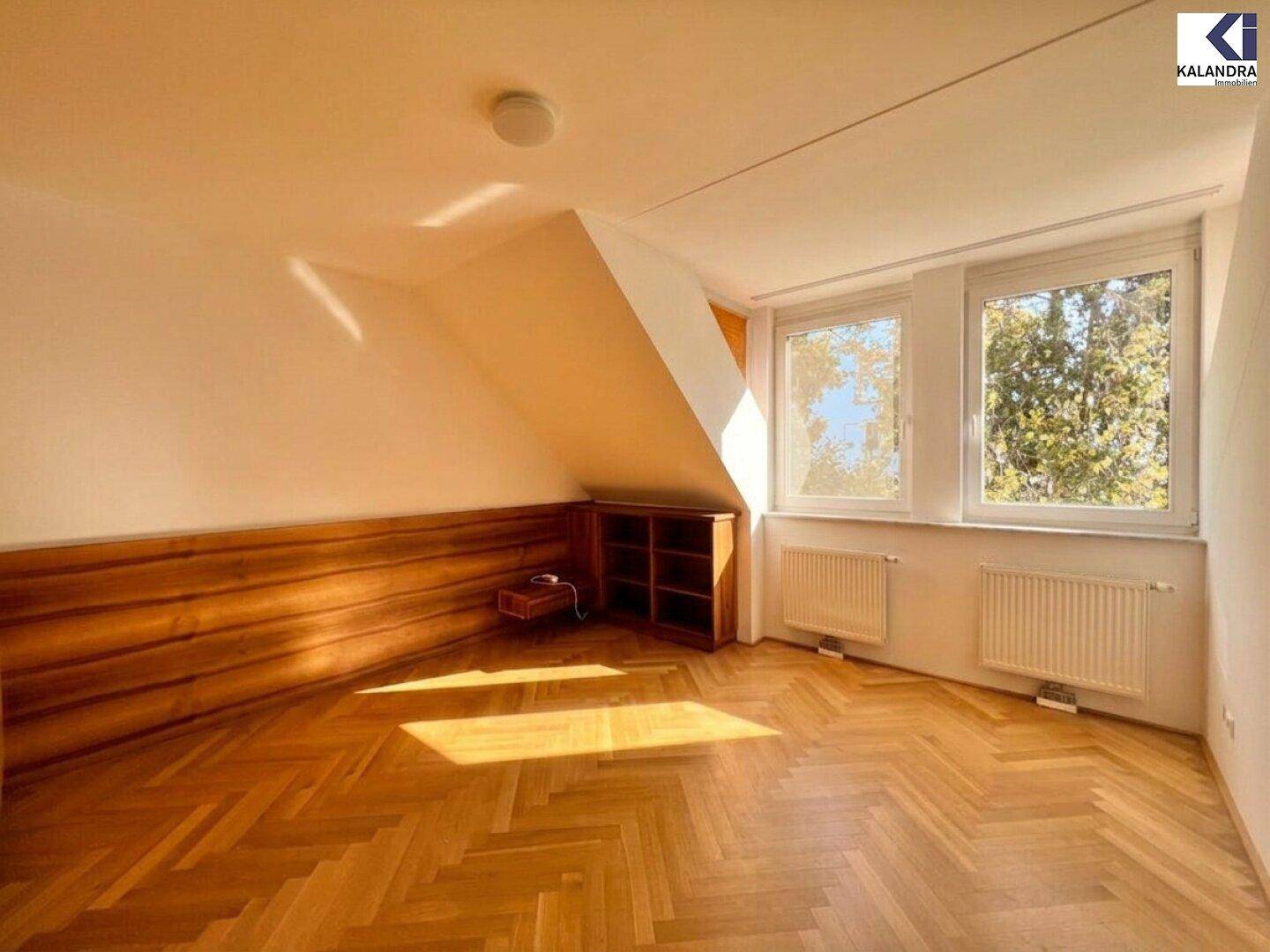 Helles Schlafzimmer mit Dachschräge, Holzvertäfelung und Fischgrätparkett.