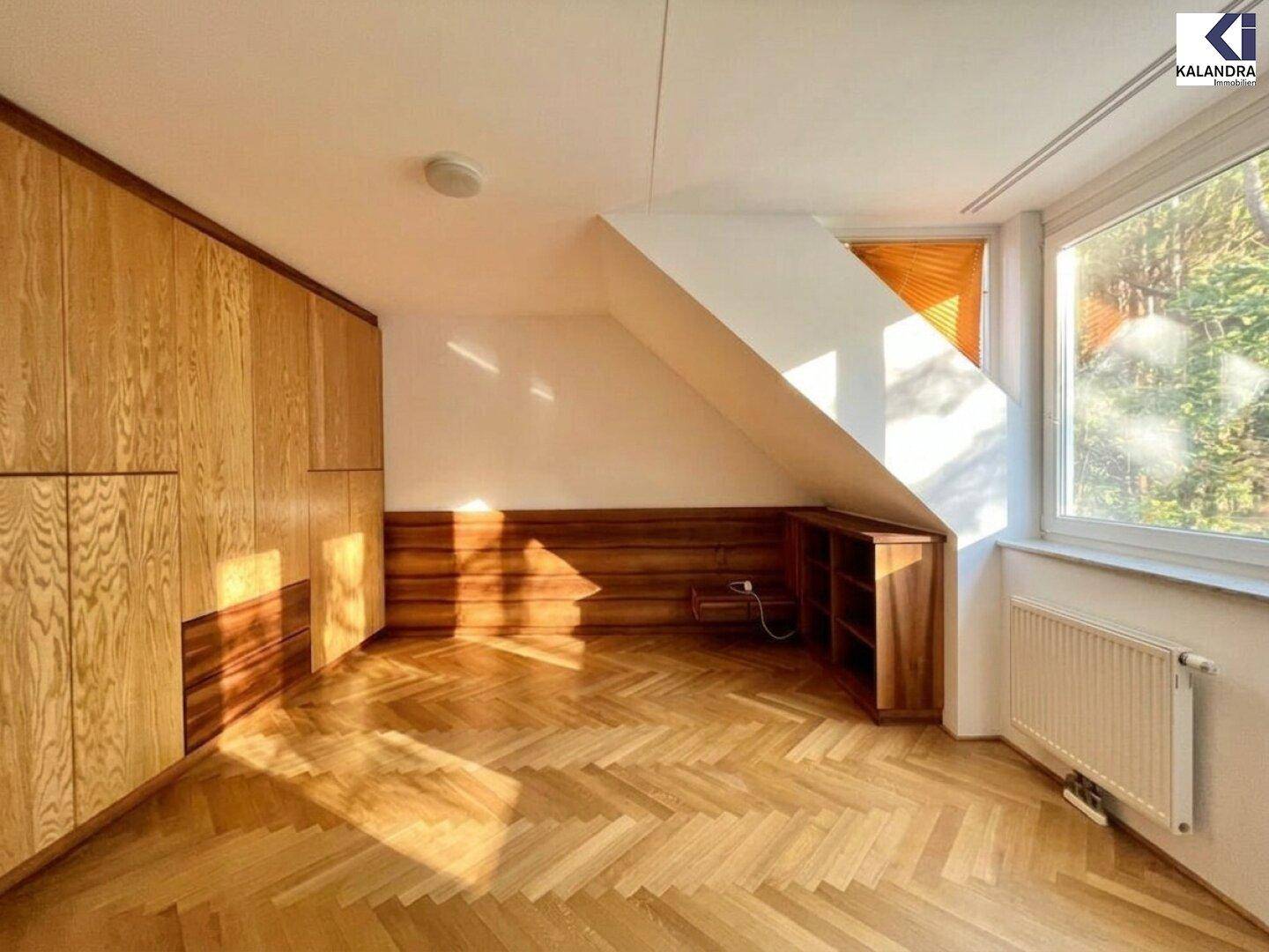 Geräumiges Schlafzimmer mit Dachschräge, großen Einbauschränken und Parkettboden.