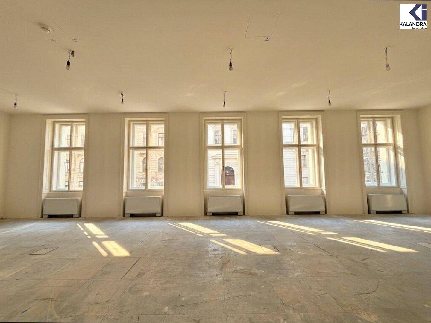 Heller Büroraum mit einer Reihe großer Fenster und viel Tageslicht.