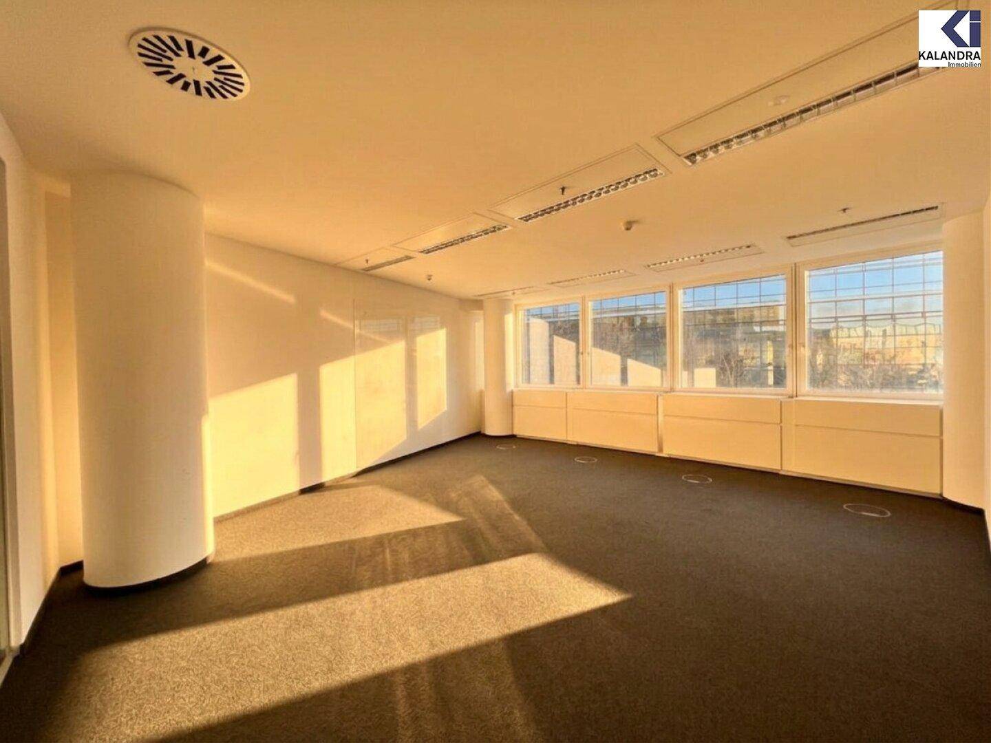 Helles Büro mit Teppichboden und Klimaanlage, durchflutet von natürlichem Sonnenlicht und mit Stadtblick.