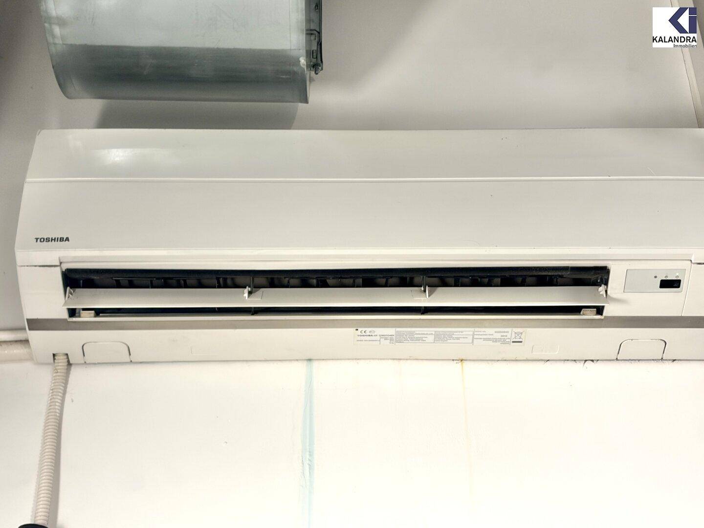 Nahaufnahme einer Toshiba Klimaanlage, die an einer weißen Wand montiert ist.
