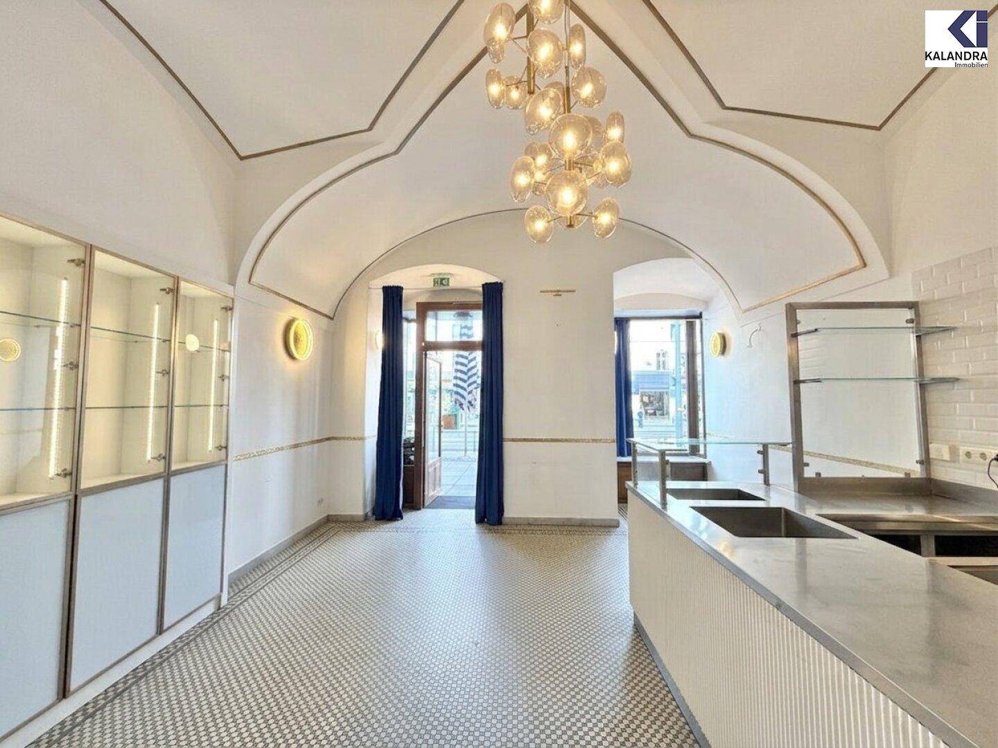 Heller Verkaufsraum mit gewölbter Decke, Mosaikboden und moderner Beleuchtung, ideal für ein Geschäft.