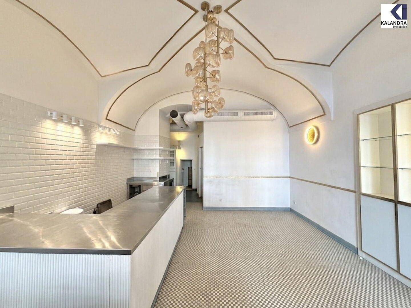 Geräumiger Verkaufsraum mit gewölbter Decke, weißer Ziegelwand und Thekenbereich, bereit zur Nutzung.
