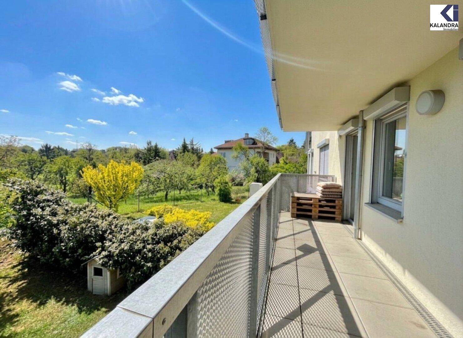 Geräumiger Balkon mit Metallgeländer und weitem Blick über grüne Gärten.
