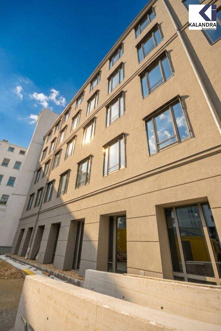 Moderne Gebäudefassade mit vielen Fenstern und klarem blauem Himmel im Hintergrund.