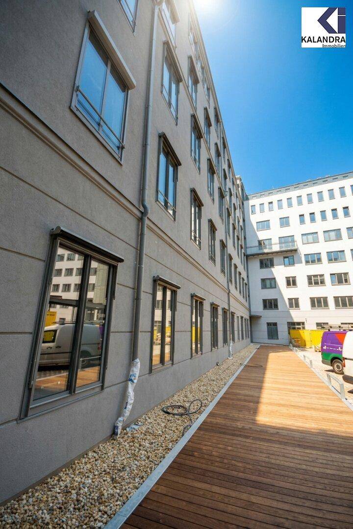 Seitenansicht eines modernen Gebäudes mit Holzterrasse und Kiesbeet unter den Fenstern.