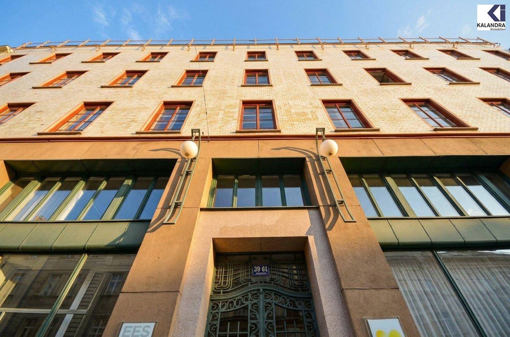 Detailansicht der Fassade eines historischen Gebäudes mit verzierten Fenstern und Eingangsbereich.