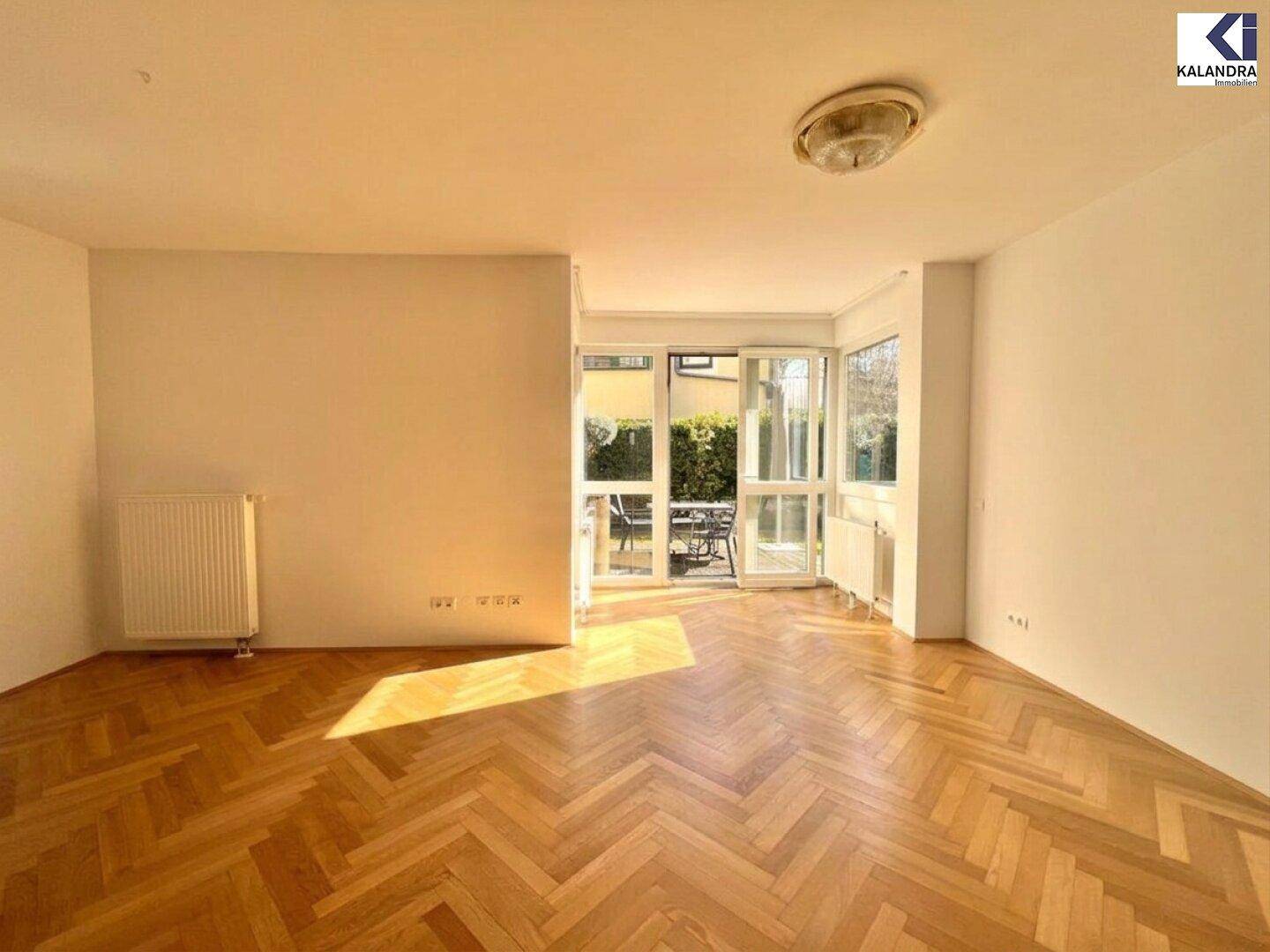 Helles Wohnzimmer mit Fischgrätparkettboden und Zugang zur Terrasse, gut beleuchtet durch Tageslicht.
