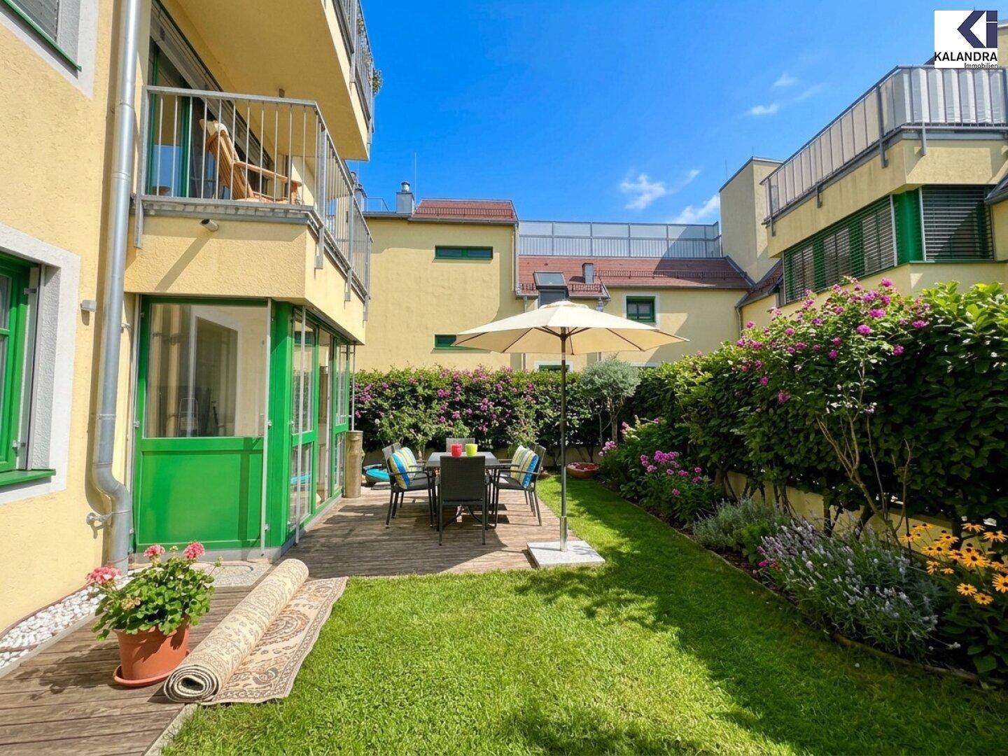 Sonniger Garten mit Holzterrasse, Sitzgelegenheiten und üppiger Bepflanzung, ideal zum Entspannen.