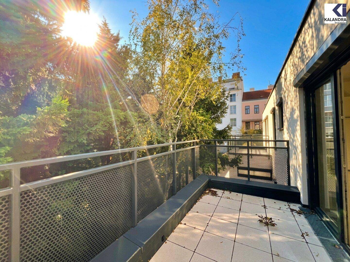 Sonnige Terrasse mit Fliesenboden und Blick auf die umliegende Bebauung und viel Grün.