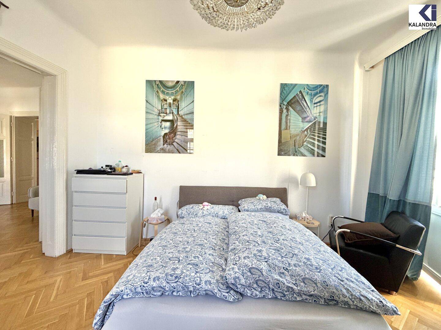 Gemütliches Schlafzimmer mit Doppelbett, Fischgrätparkett und elegantem Kronleuchter.