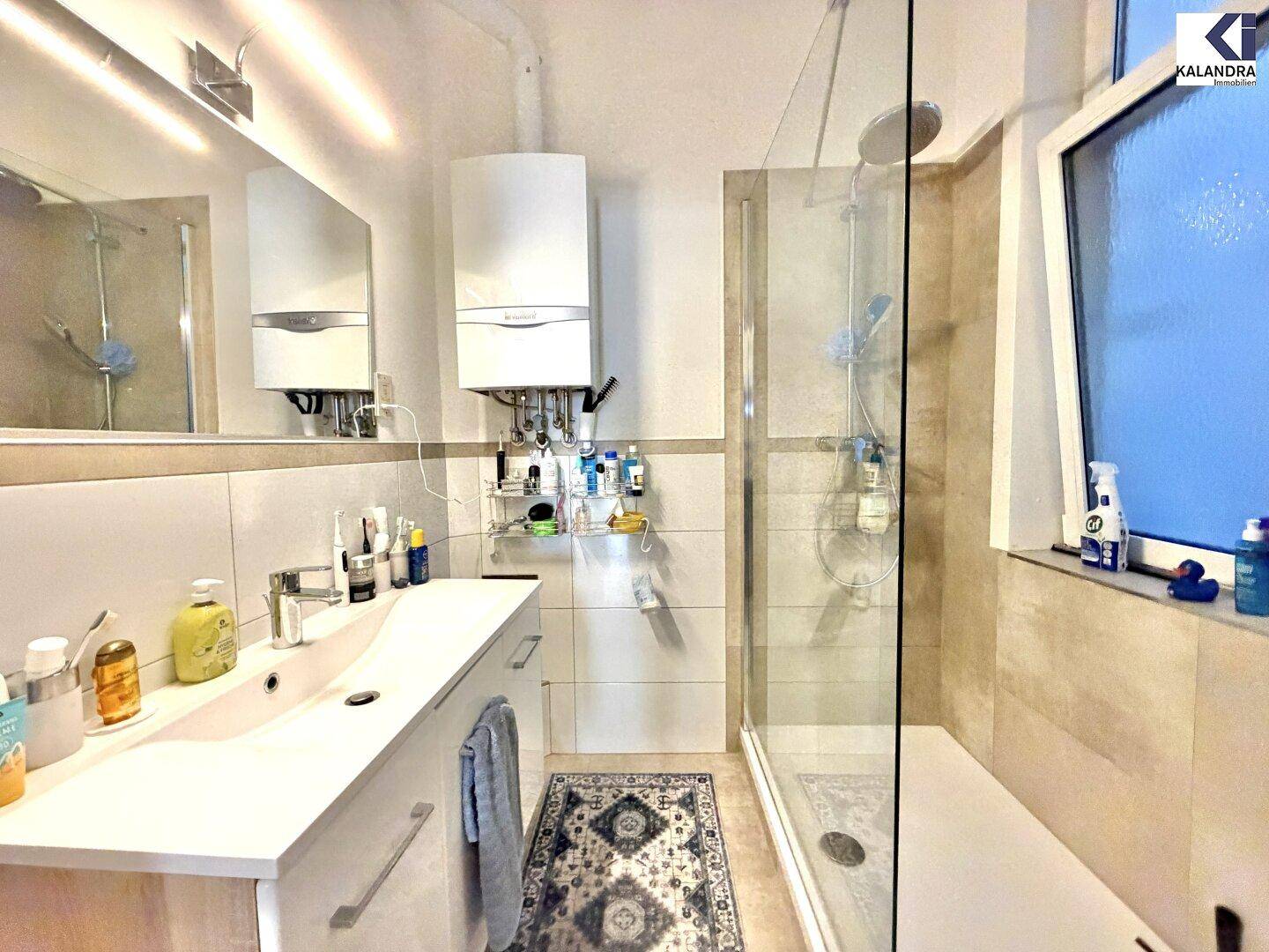 Modernes Badezimmer mit Duschkabine, Einzelwaschbecken und Fenster für Tageslicht.