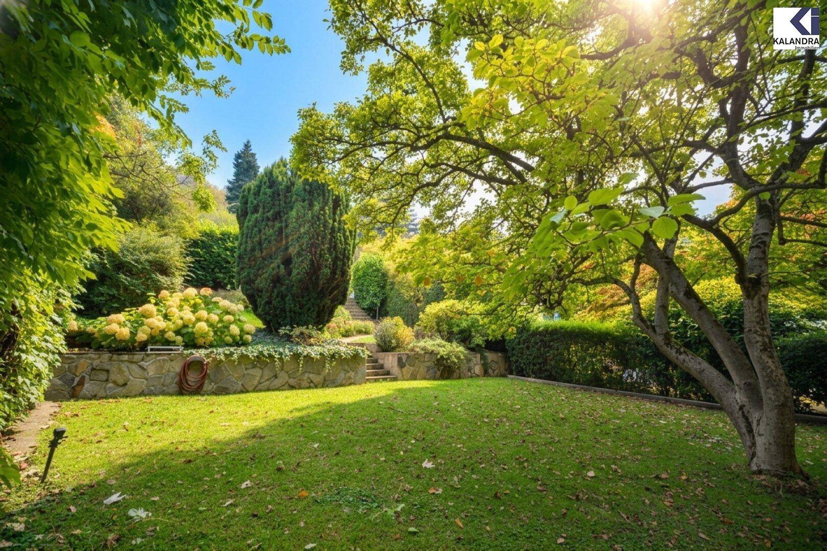 Sonniger Garten mit gepflegtem Rasen, alten Bäumen und üppiger Bepflanzung auf verschiedenen Ebenen.