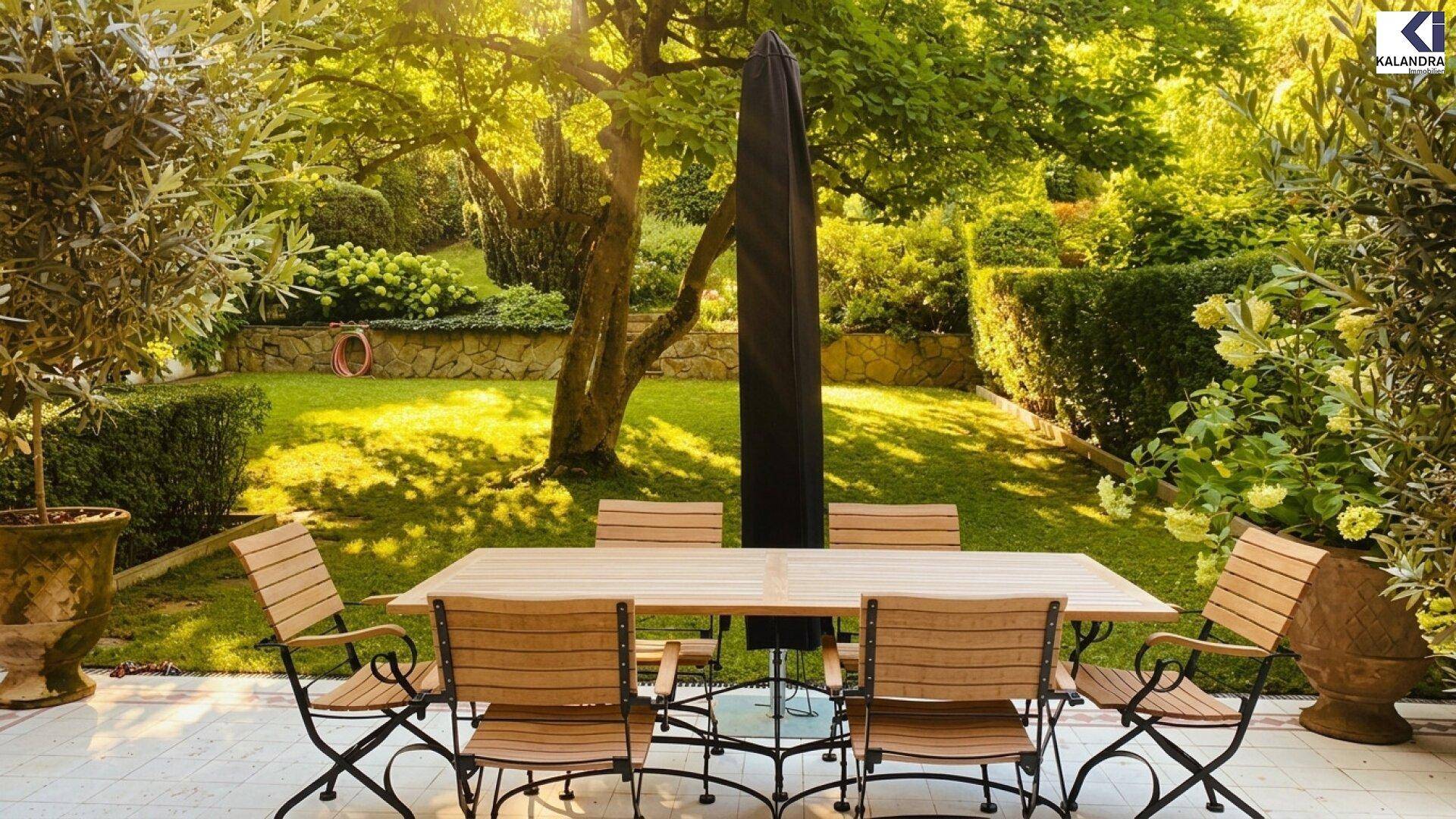 Gemütlicher Essbereich im Freien auf einer gefliesten Terrasse, umgeben von einem üppigen Garten mit Bäumen.