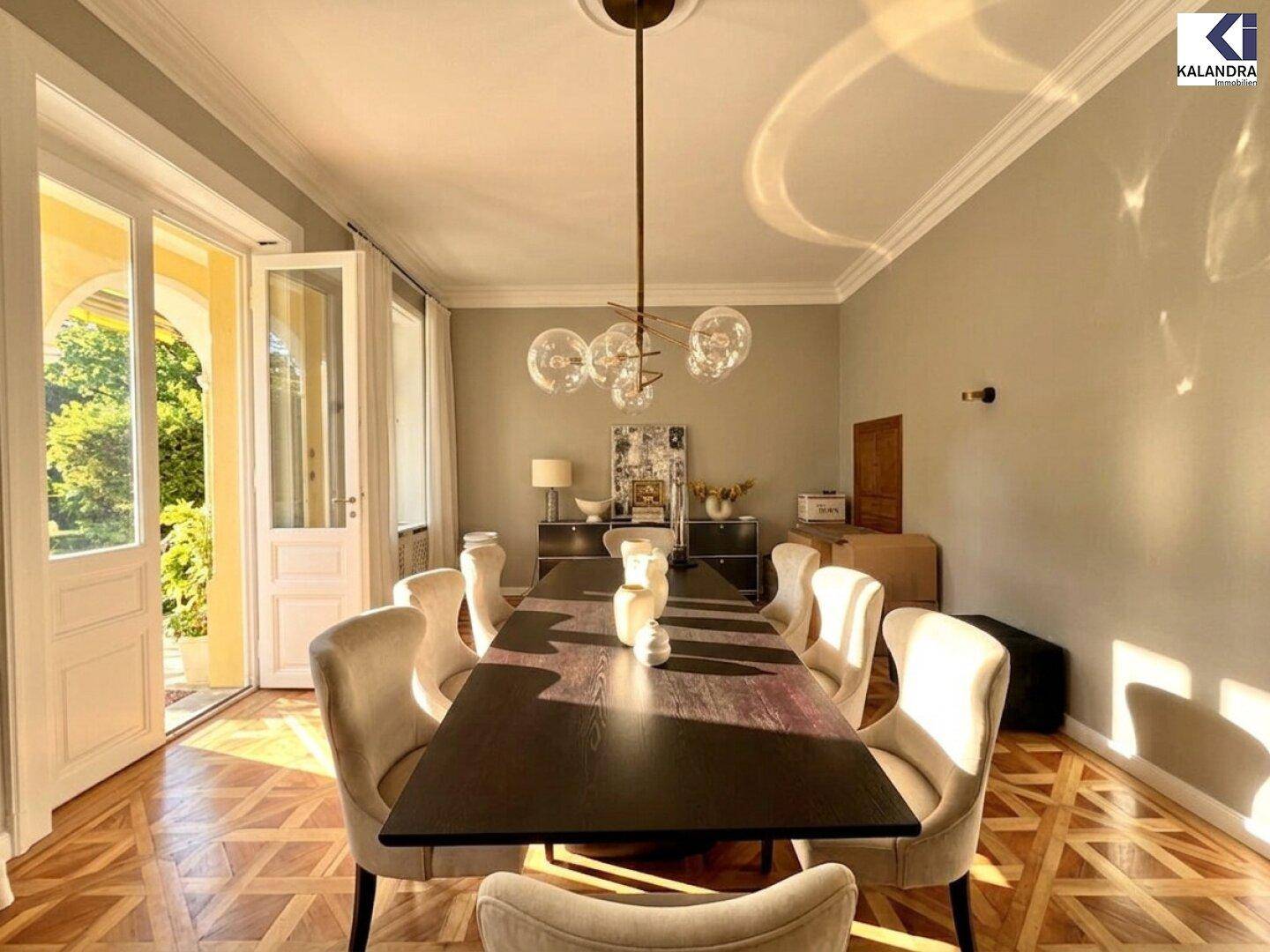Eleganter Essbereich mit großem Tisch und direktem Zugang zu einer überdachten Loggia oder Terrasse.