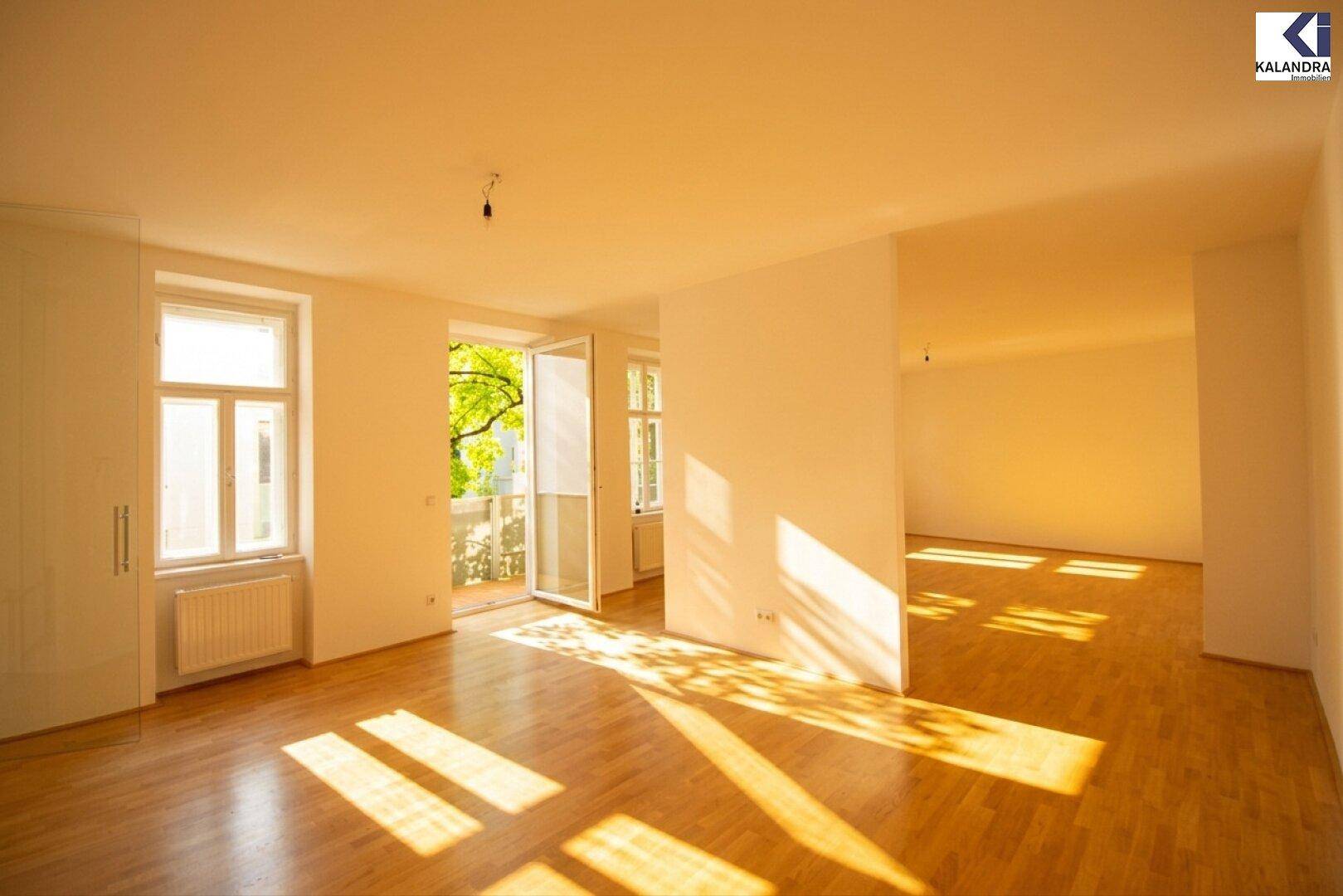 Heller Wohnraum mit Parkettboden, Einbauschrank und Zugang zu einem sonnigen Balkon.
