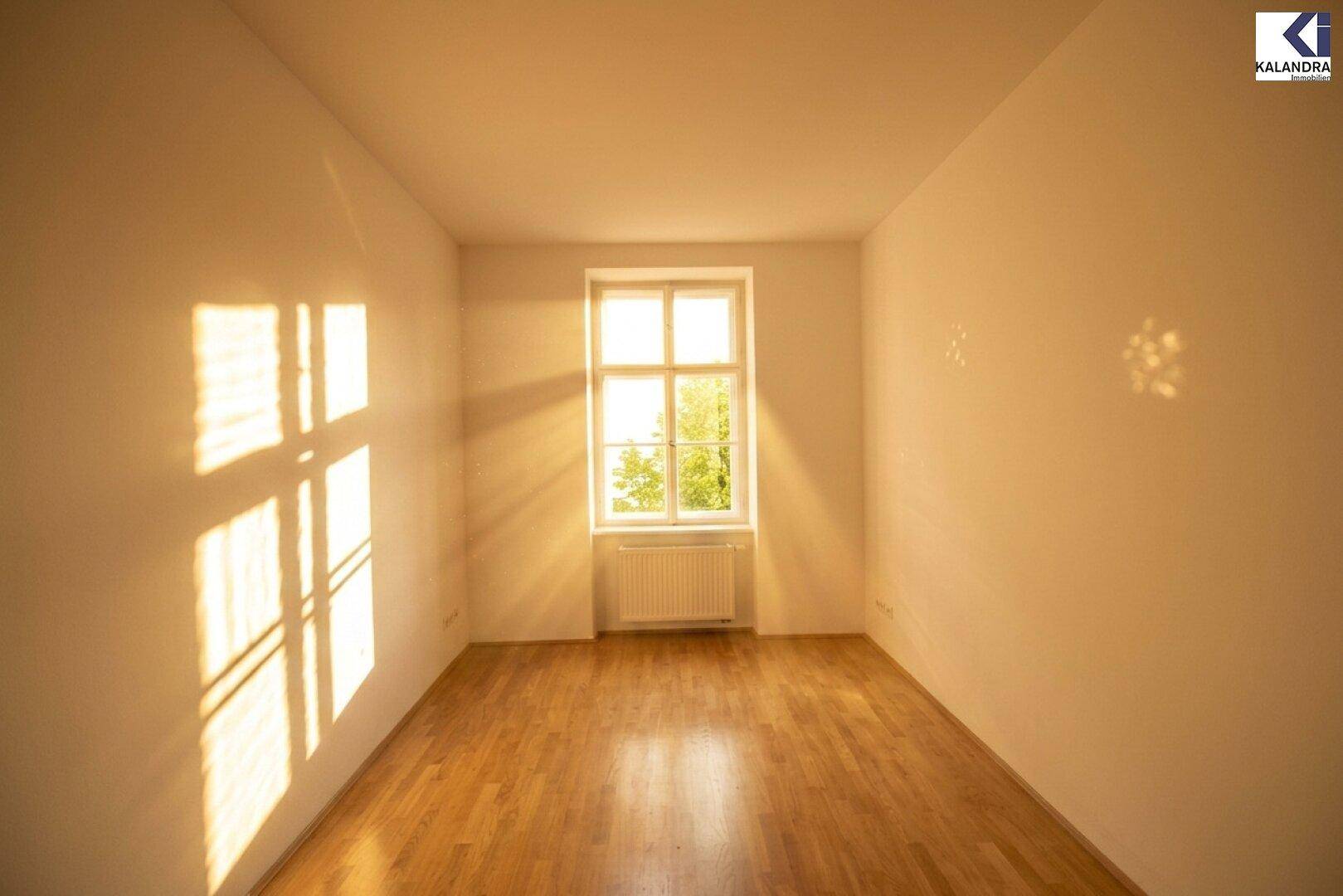 Ruhiges Schlafzimmer mit Parkettboden und einem Fenster, das viel Sonnenlicht hereinlässt.