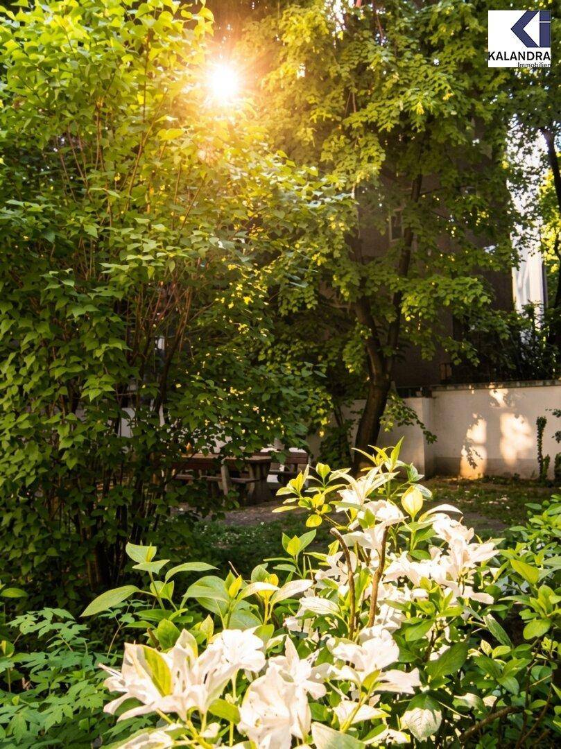 Sonnige Gartenoase mit üppiger Vegetation, blühenden Pflanzen und schattigem Sitzbereich.
