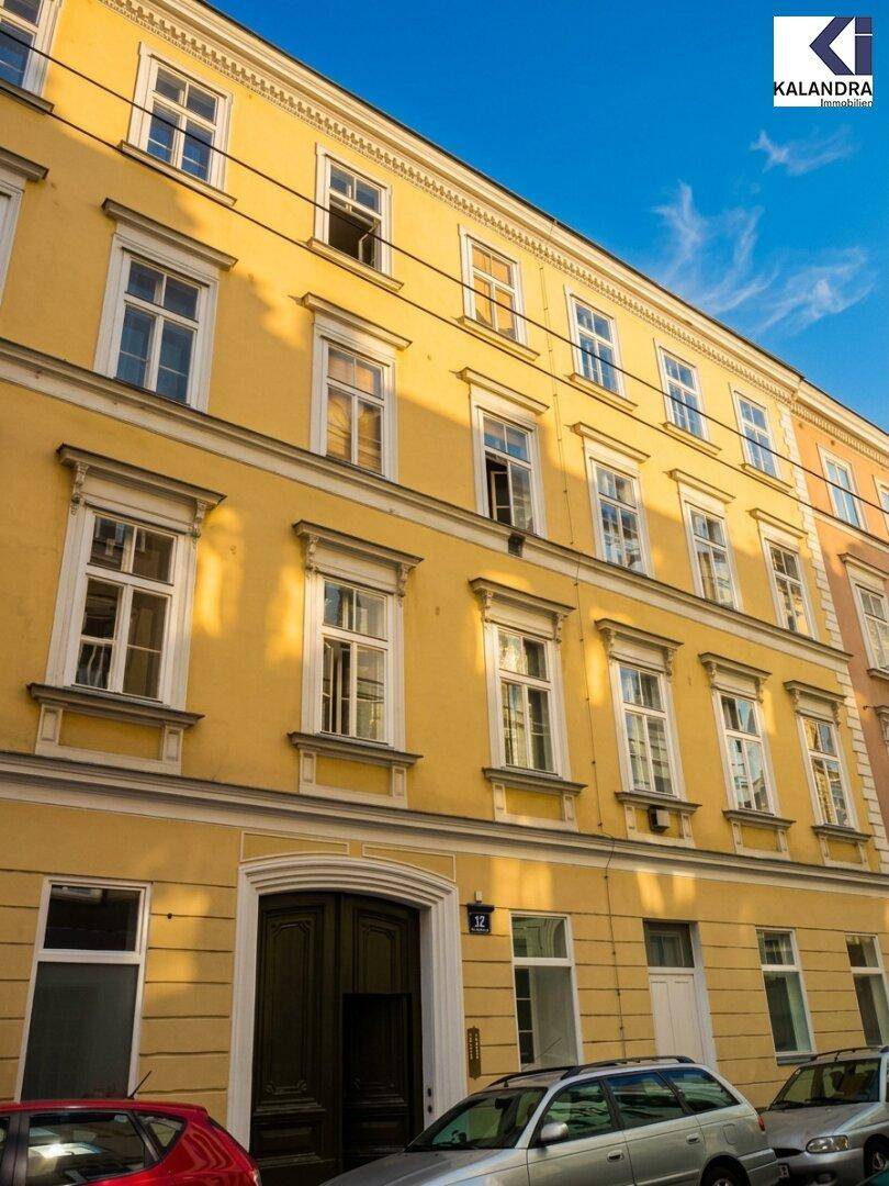Klassische gelbe Fassade eines Mehrfamilienhauses mit vielen Fenstern und traditioneller Architektur.