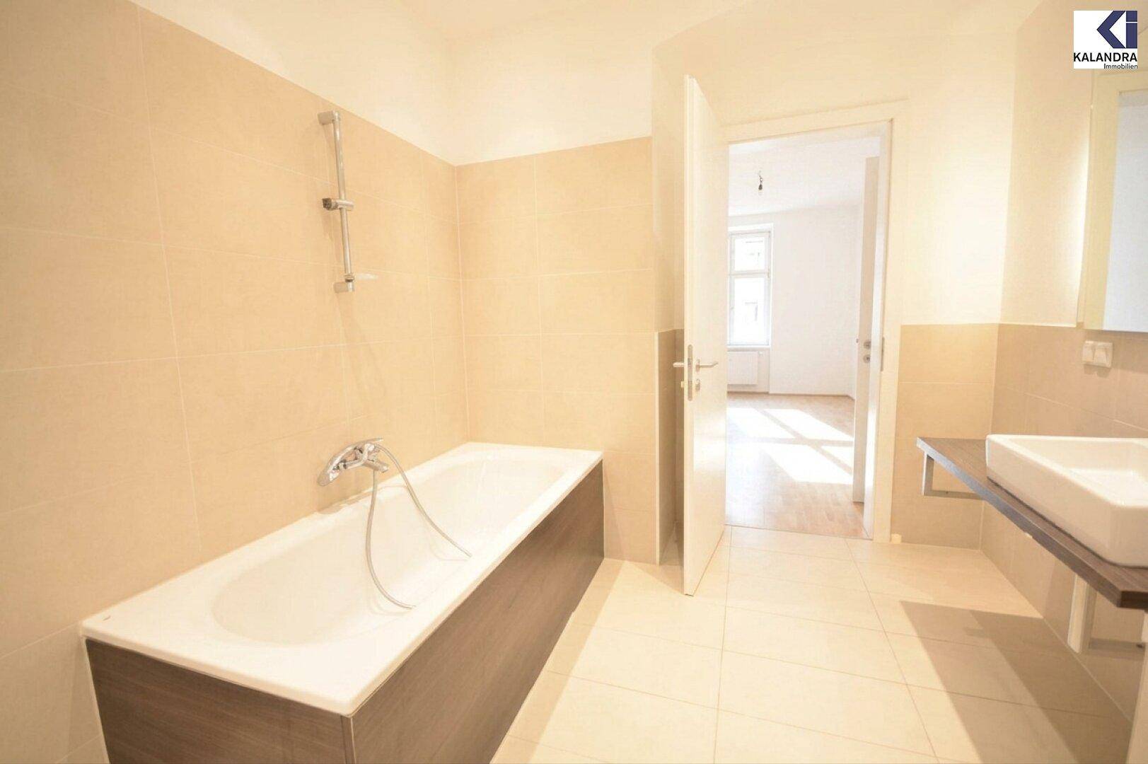 Helles Badezimmer mit Badewanne, Duscharmatur und modernem Waschtisch mit Spiegel.