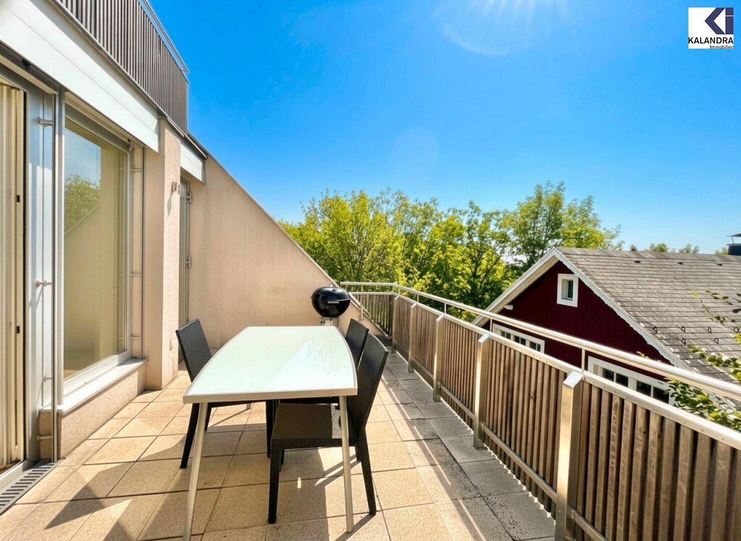 Heller Balkon mit Esstisch und Grill, bietet eine schöne Aussicht auf die Umgebung.