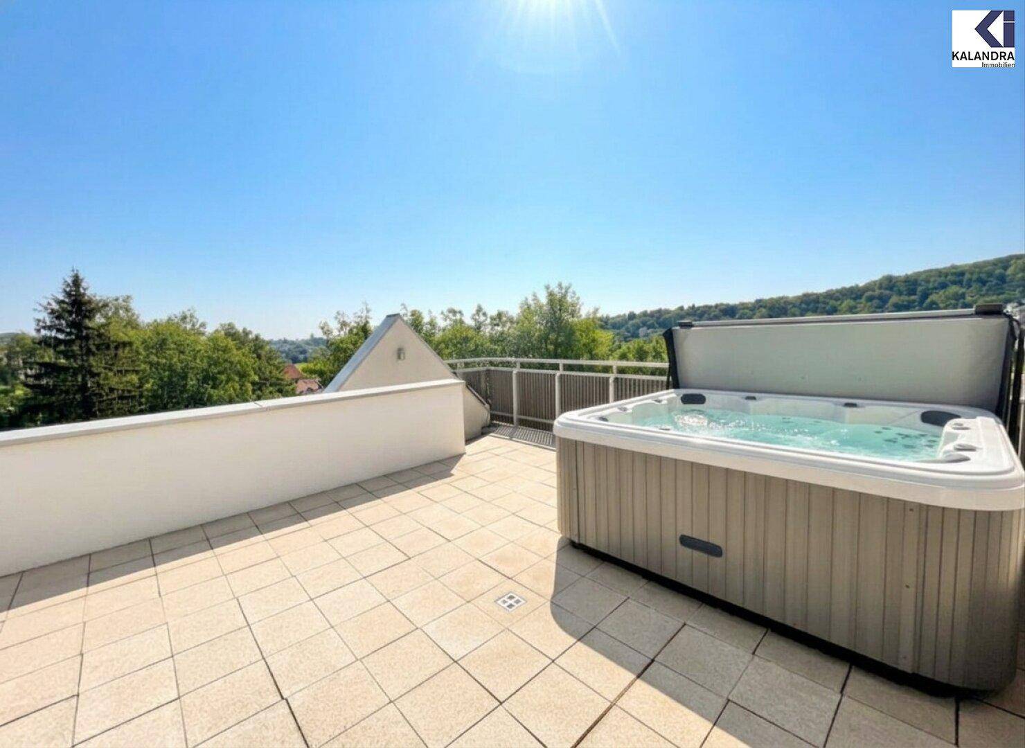 Sonnenterrasse mit geöffnetem Whirlpool, bereit für entspannende Stunden im Freien.