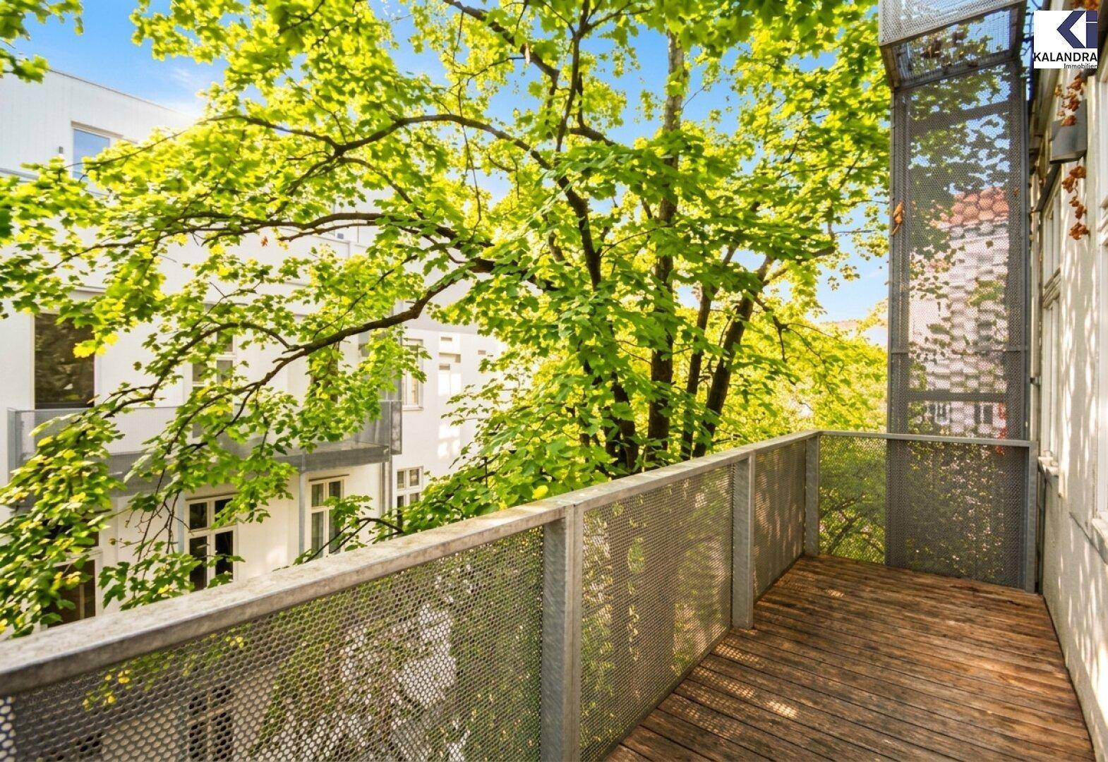 Geräumiger Balkon mit Holzfußboden und Metallgeländer, umgeben von Bäumen.