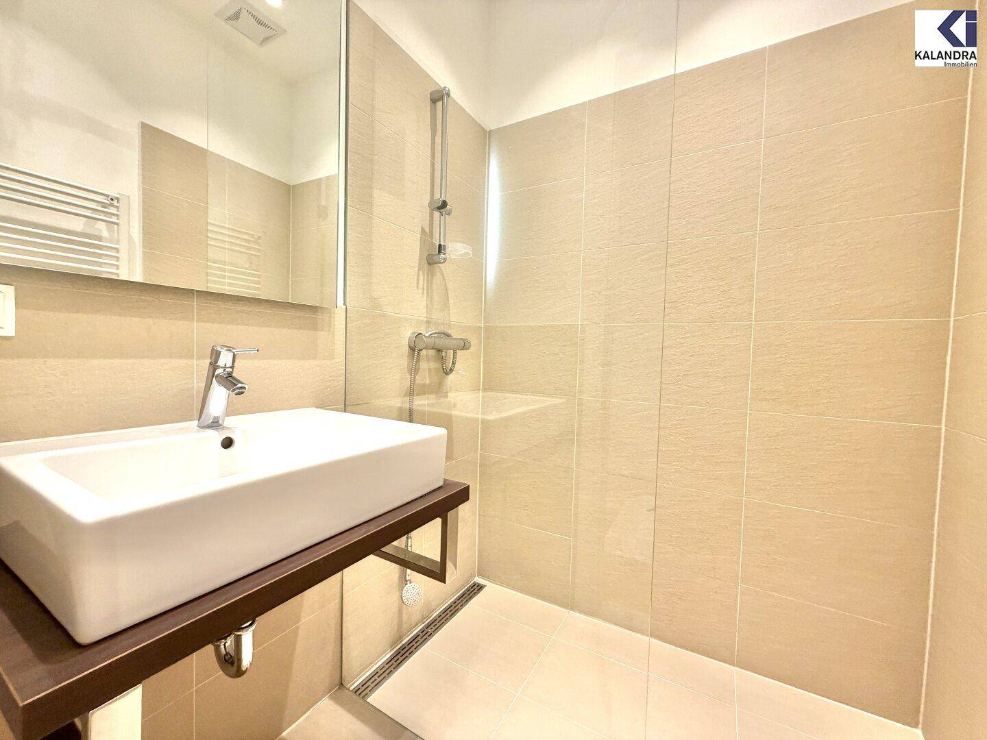 Modernes Badezimmer mit begehbarer Dusche, Einzelwaschbecken und beheiztem Handtuchhalter.
