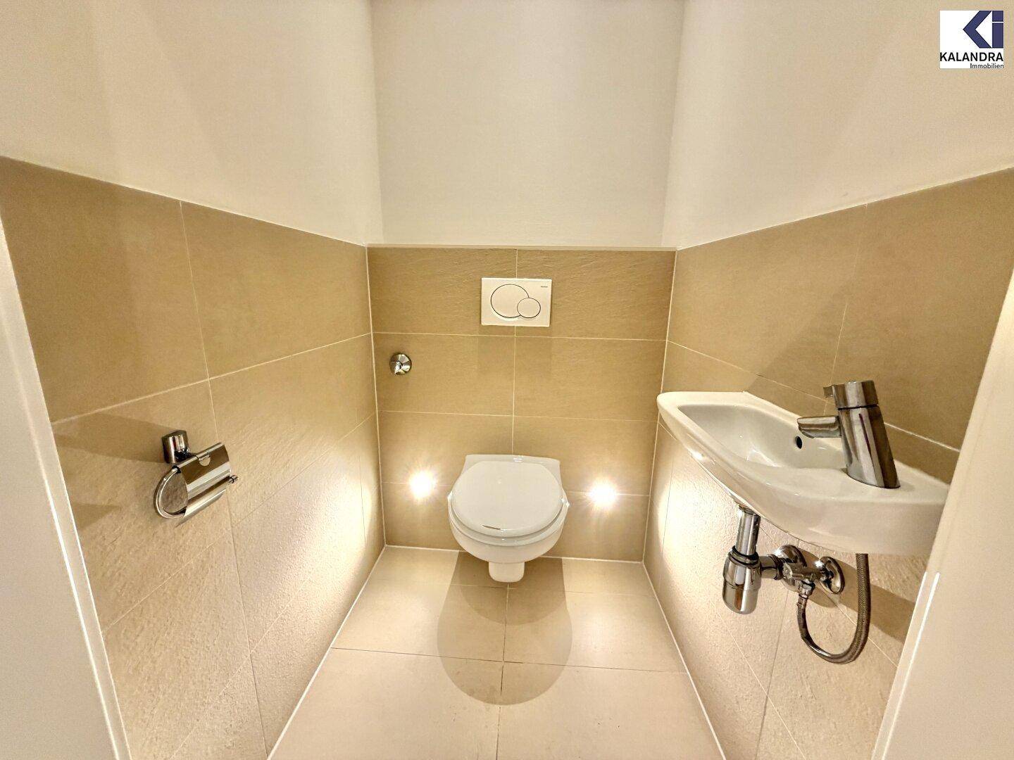 Kleines Gäste-WC mit Wand-WC, kleinem Waschbecken und indirekter Beleuchtung.