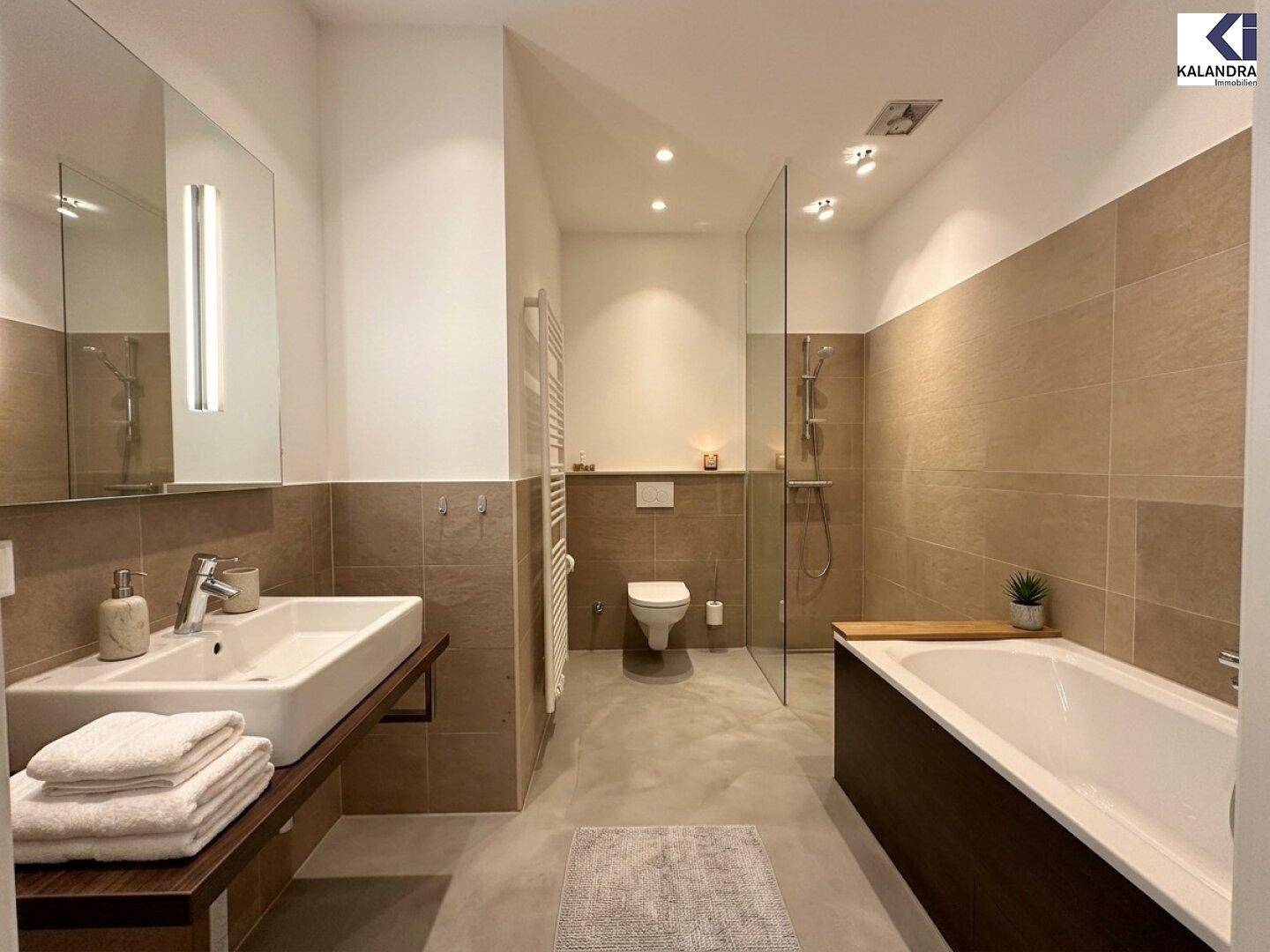 Geräumiges, modernes Badezimmer mit Badewanne, ebenerdiger Dusche und Waschtisch.