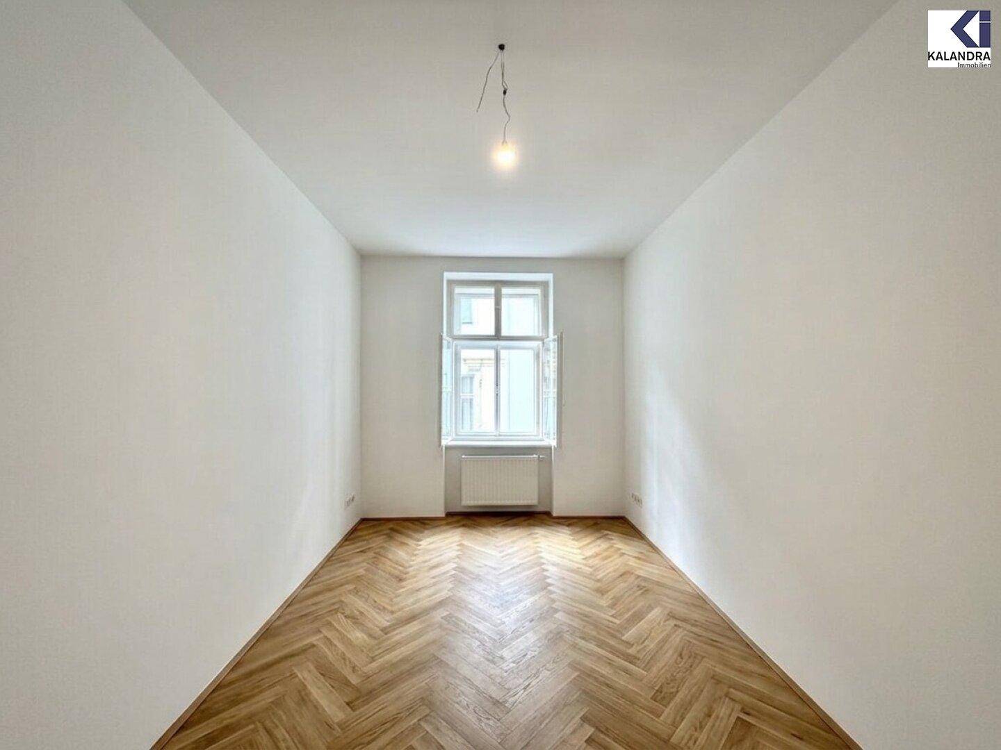 Gemütliches Zimmer mit klassischem Fischgrätparkett und einem Fenster für natürliches Licht.