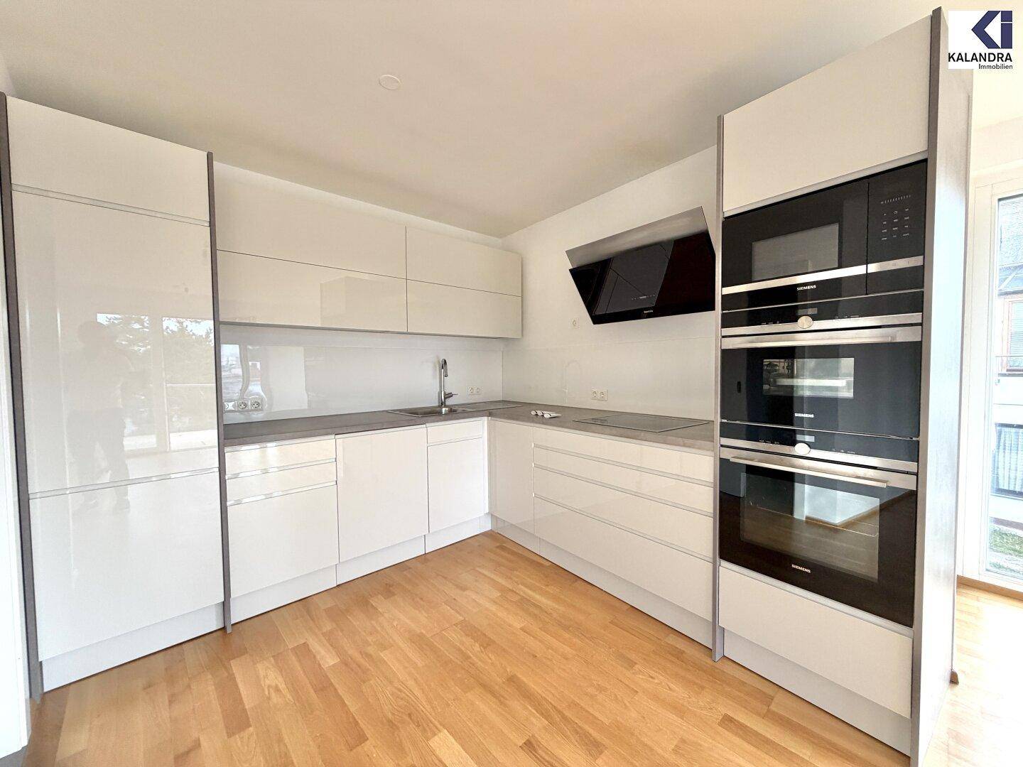 Moderne Einbauküche mit weißen Hochglanzfronten und hochwertigen Geräten.
