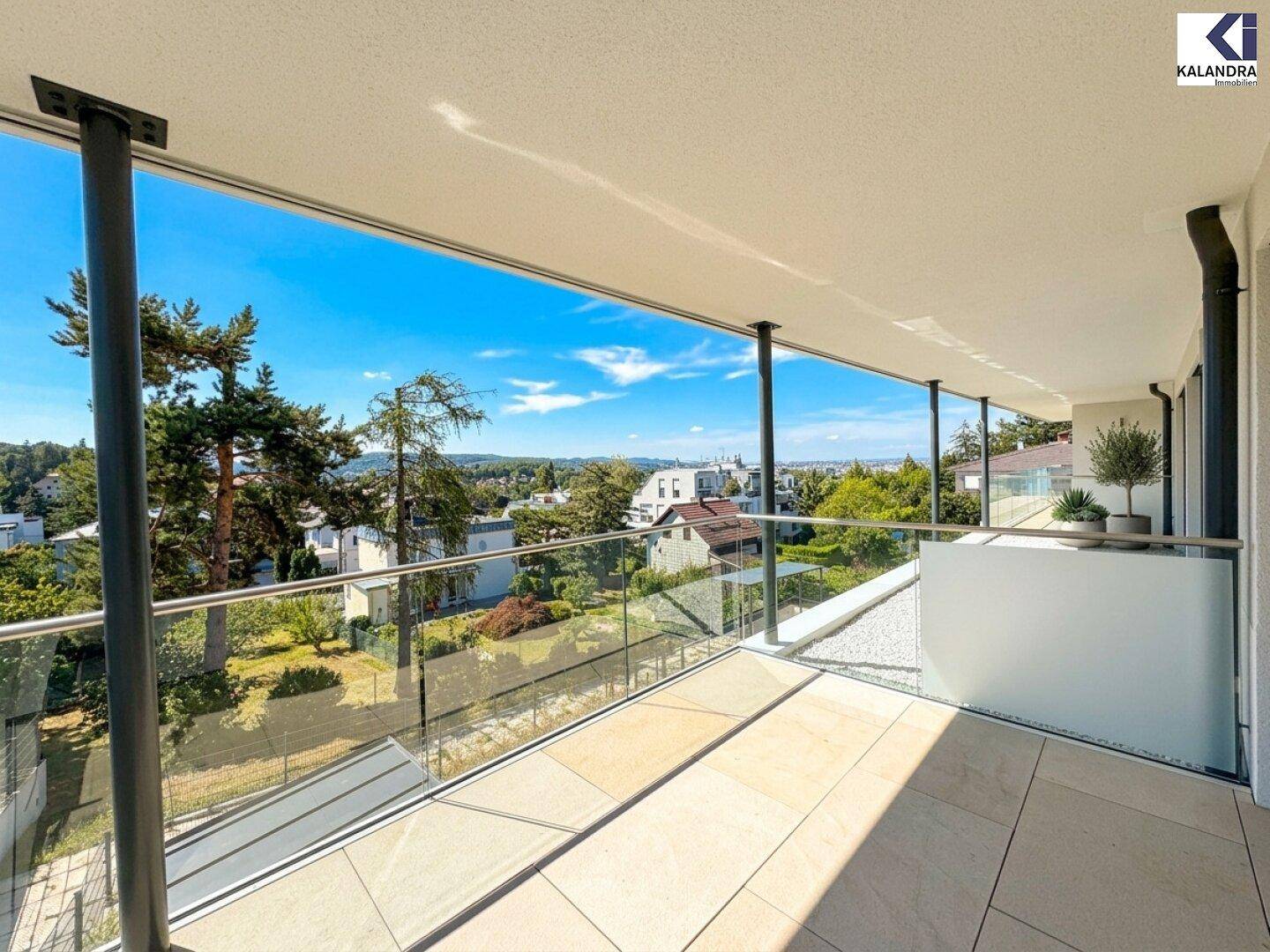 Großer Balkon mit Glasgeländer und Panoramablick über die Stadt und den See.