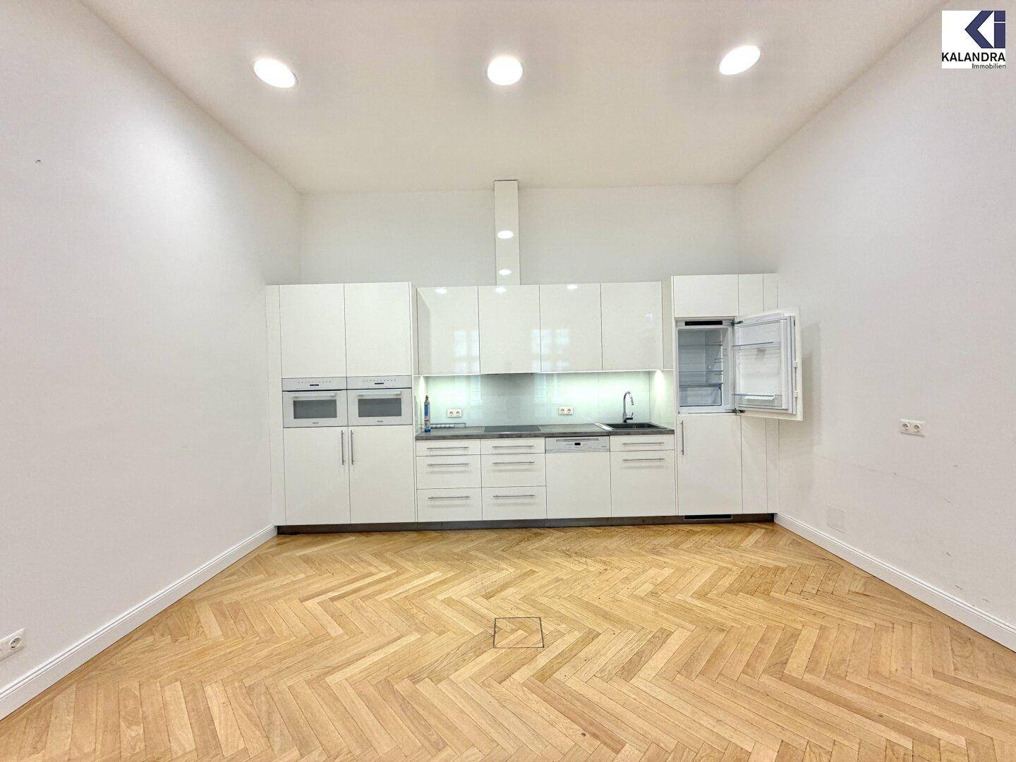 Voll ausgestattete, moderne Küche mit weißen Hochglanzfronten, integrierten Geräten und viel Stauraum.
