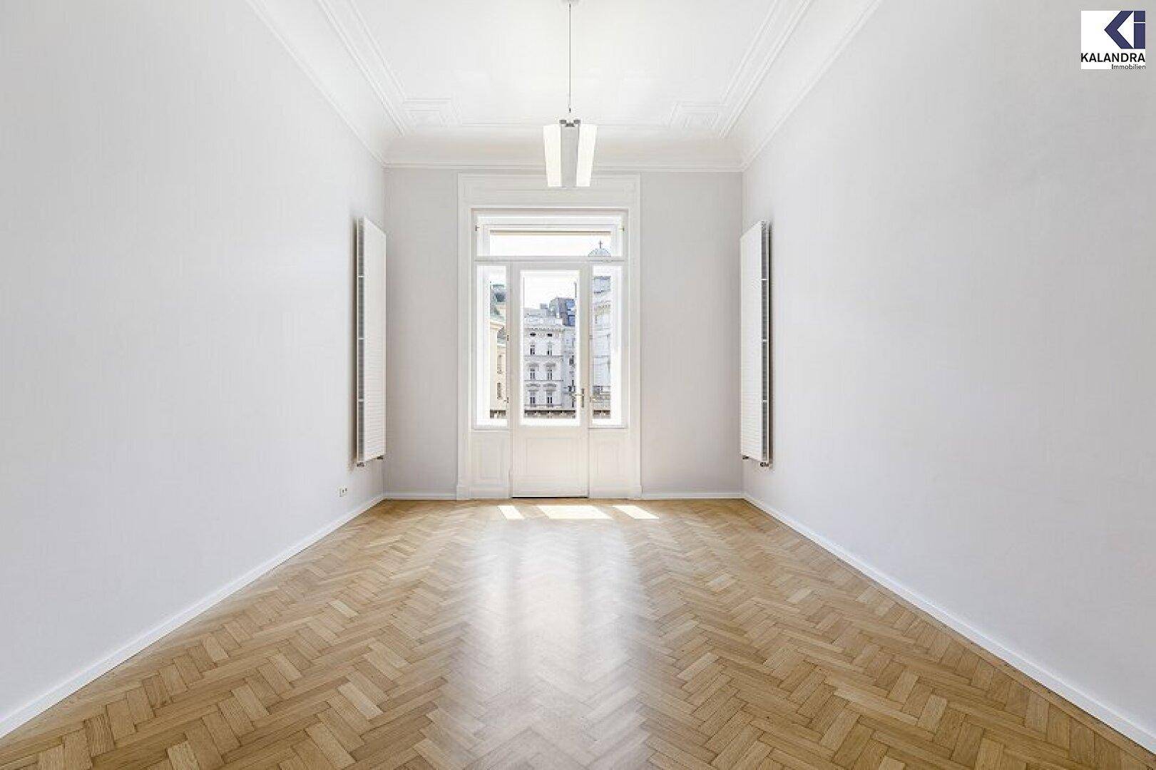 Symmetrischer Raum mit hellem Fischgrätparkett, hohen Decken und einem großen Fenster, das viel Licht hereinlässt.