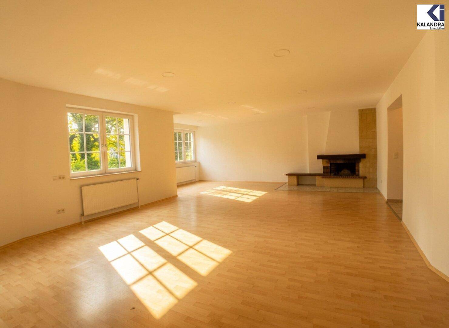 Großzügiger Wohnraum mit Kamin und hellem Parkettboden, der von Sonnenlicht durchflutet wird.