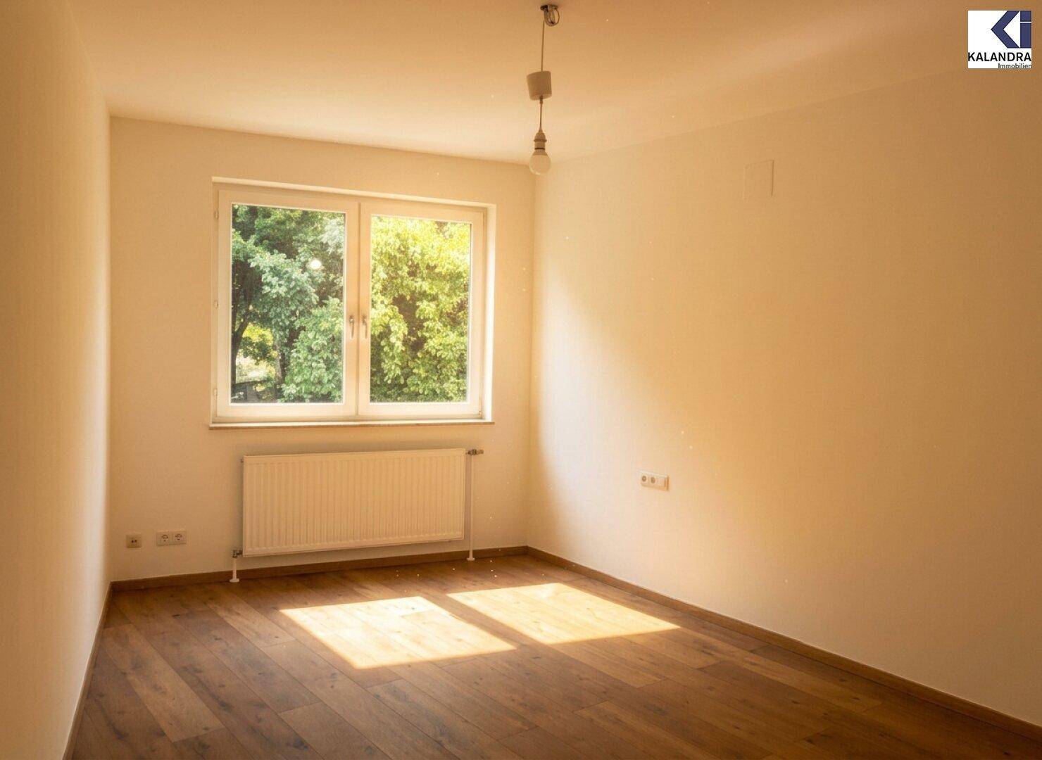 Helles Schlafzimmer mit Holzboden und einem Fenster mit Blick auf Bäume.