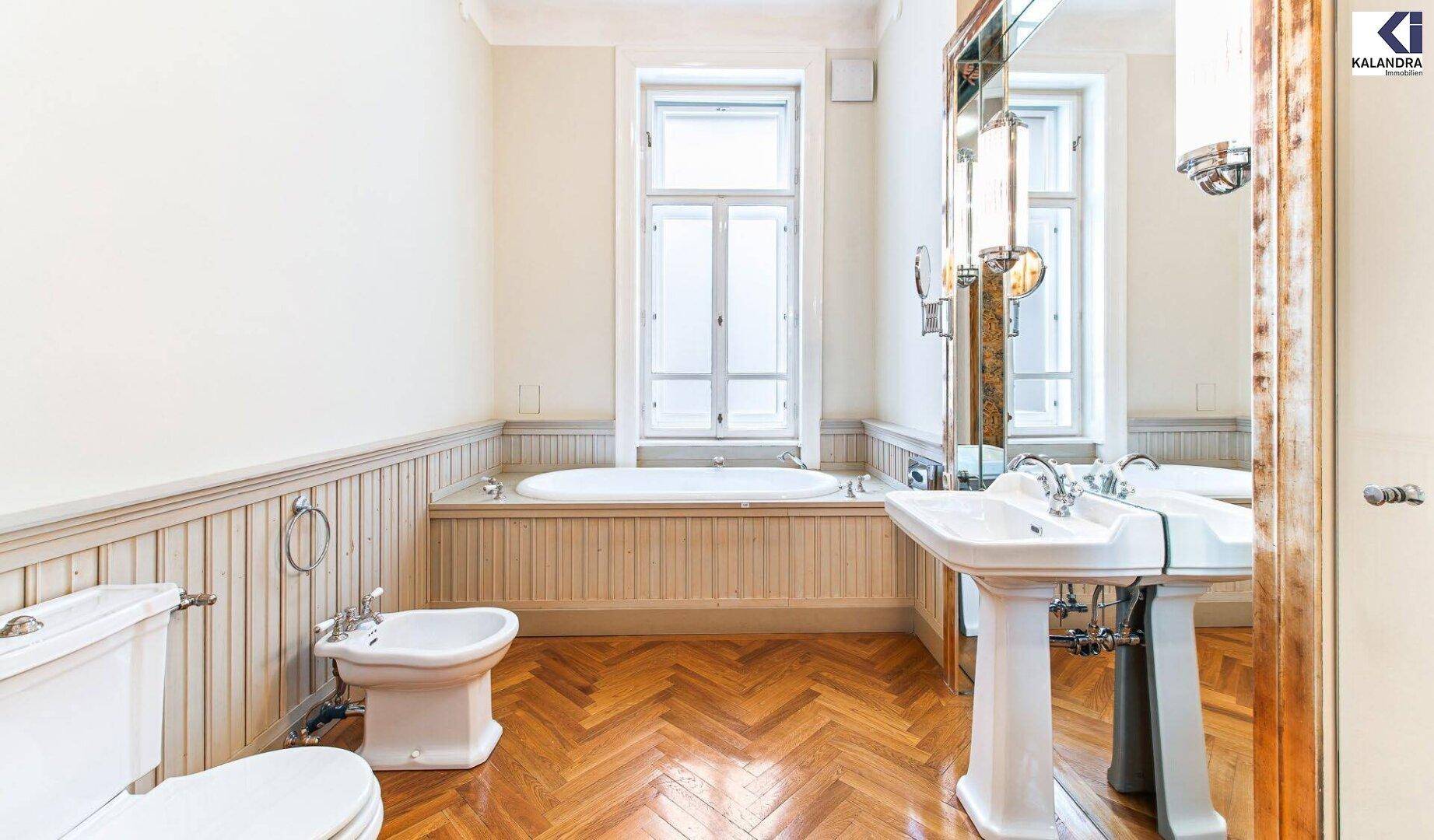 Klassisches Badezimmer mit Badewanne, Bidet, Standwaschbecken und hellem Fischgrätparkett.