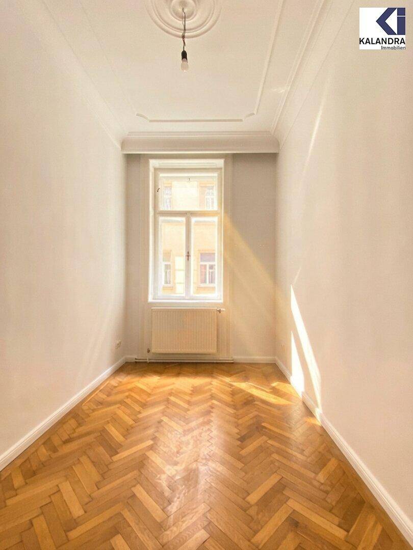 Gemütliches Schlafzimmer mit Fischgrätparkett, einem großen Fenster und viel natürlichem Licht, ideal für Ruhe.