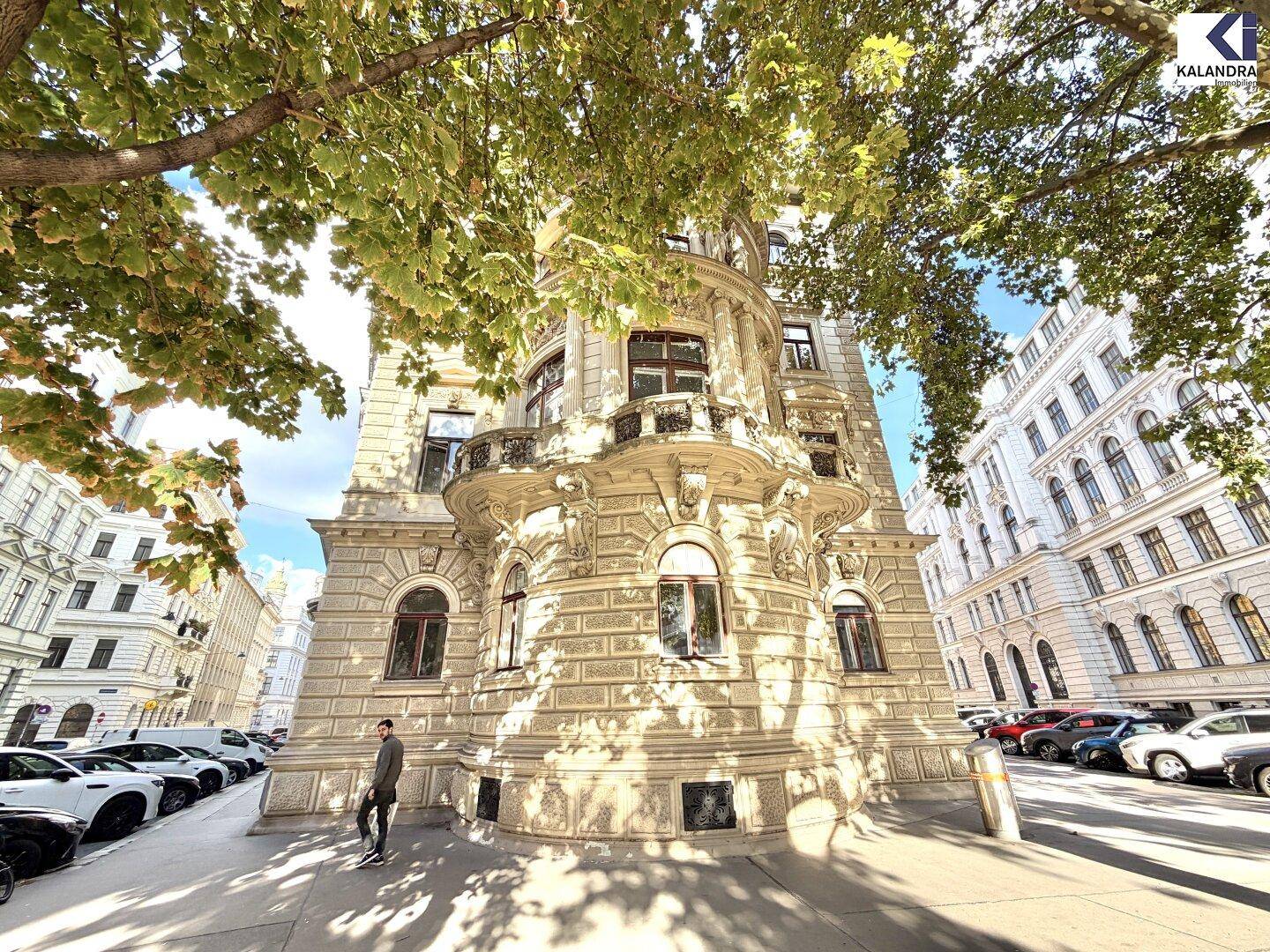 Beeindruckendes Eckgebäude mit historischer Architektur und Bäumen an der Straße, das eine städtische Ansicht bietet.