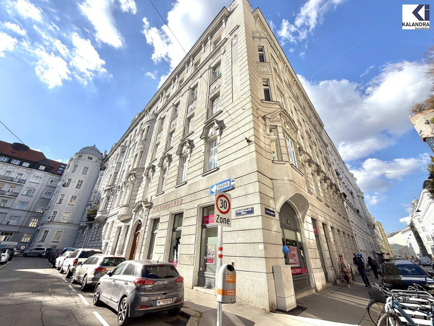 Historisches Eckgebäude mit klassischer Architektur und Geschäften im Erdgeschoss.