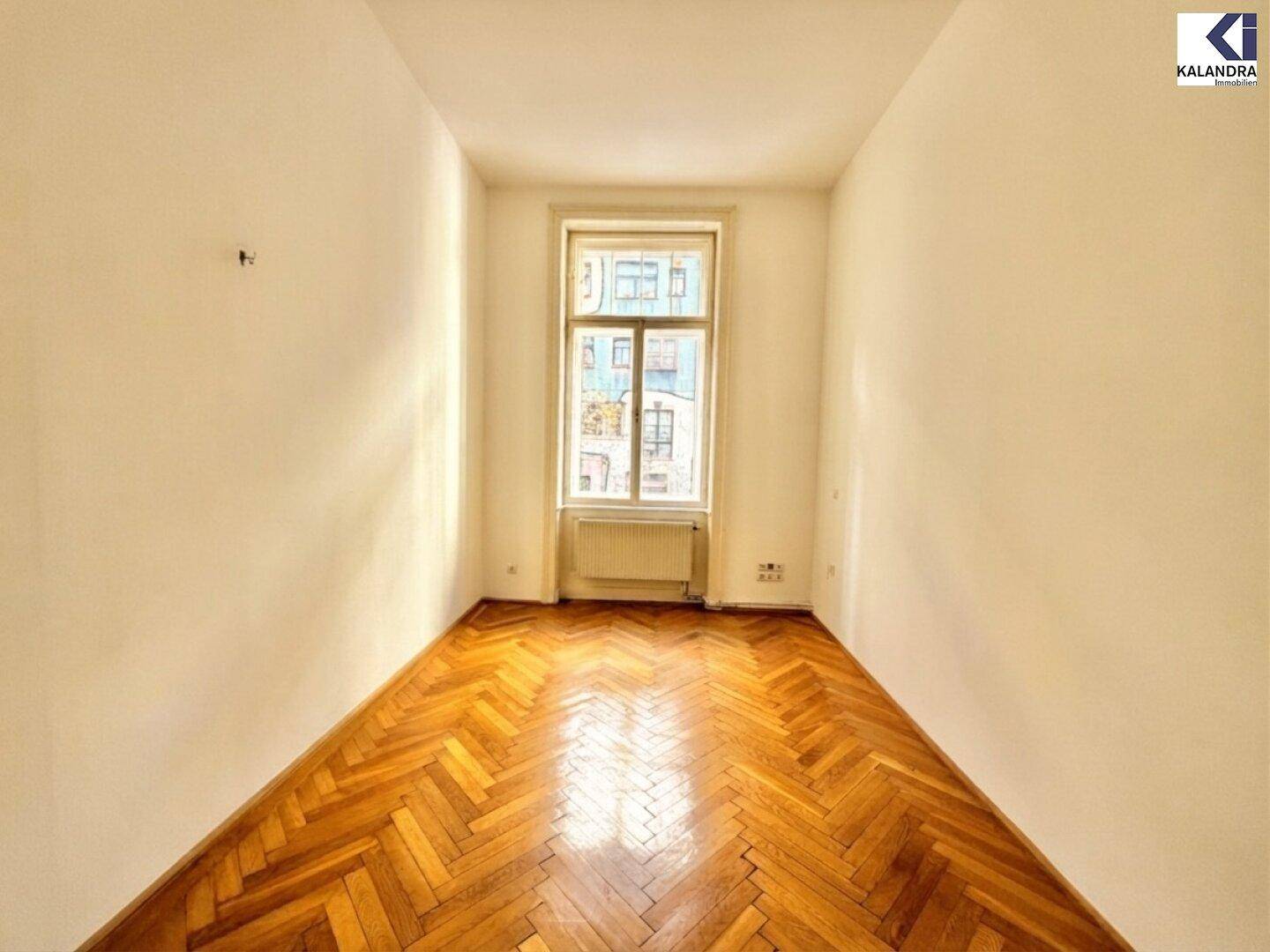 Ruhiges Schlafzimmer mit Fischgrätparkett und einem Fenster mit Blick nach draußen.
