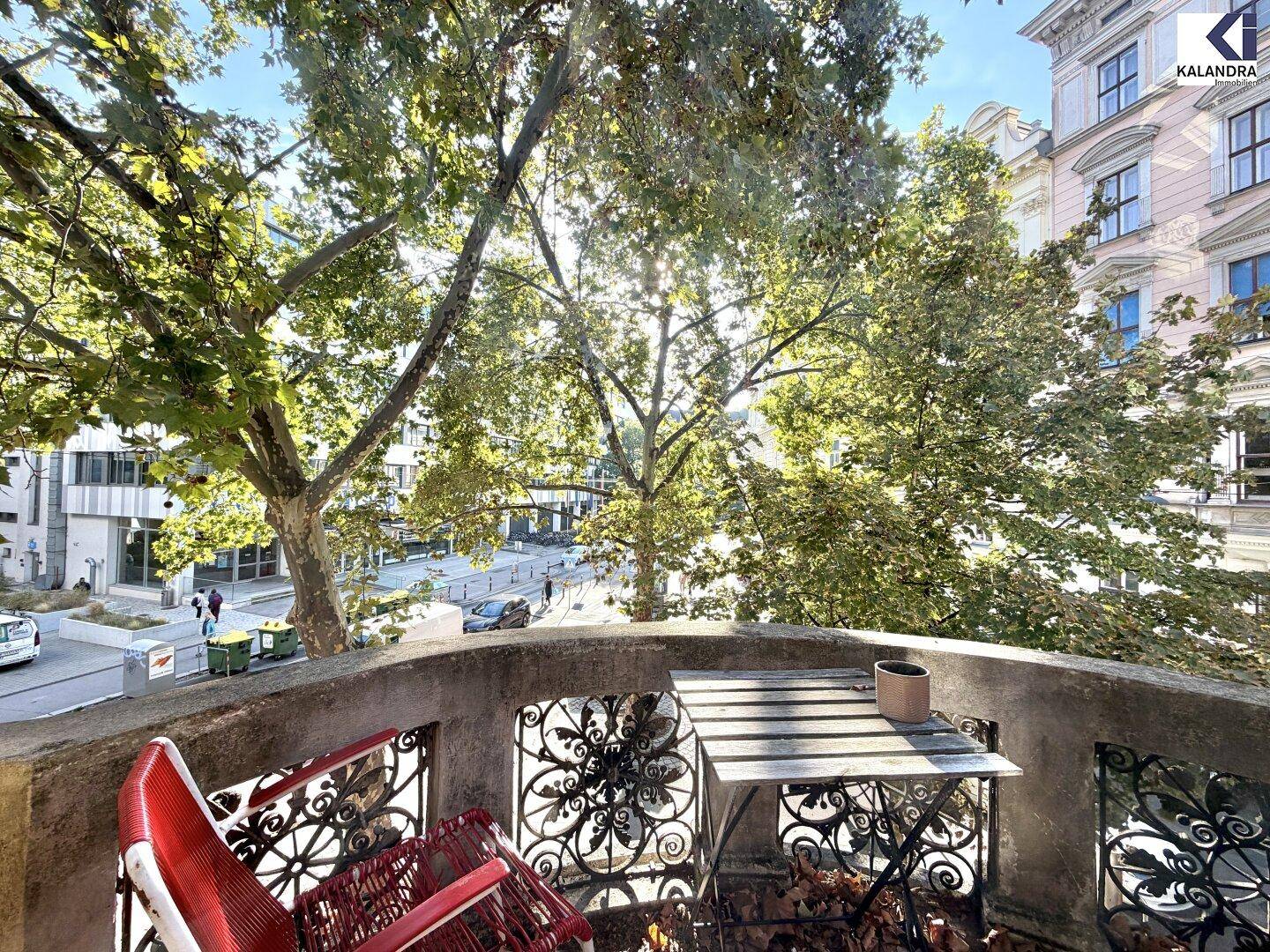 Gemütlicher Balkon mit schmiedeeisernen Möbeln und Blick auf die Stadt und Bäume.