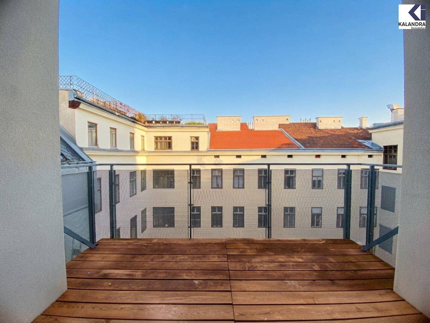 Balkon mit Holzboden und Metallgeländer, bietet einen ruhigen Blick auf den Innenhof.