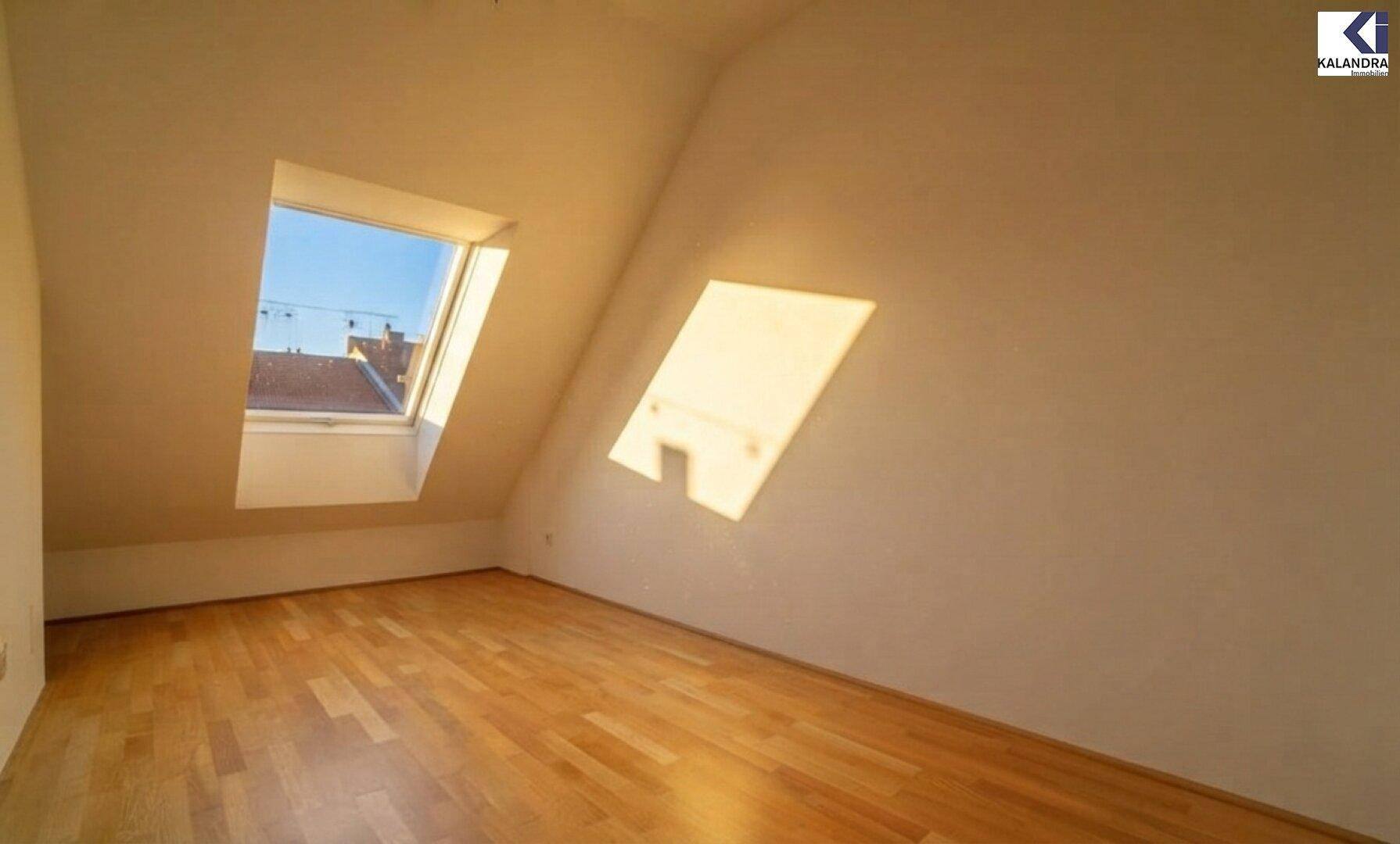 Heller Raum mit Holzboden, Dachschräge und Dachfenster, ideal für ein Schlafzimmer.