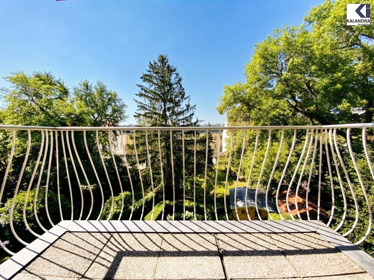 Balkon mit schmiedeeisernem Geländer und Blick ins Grüne.