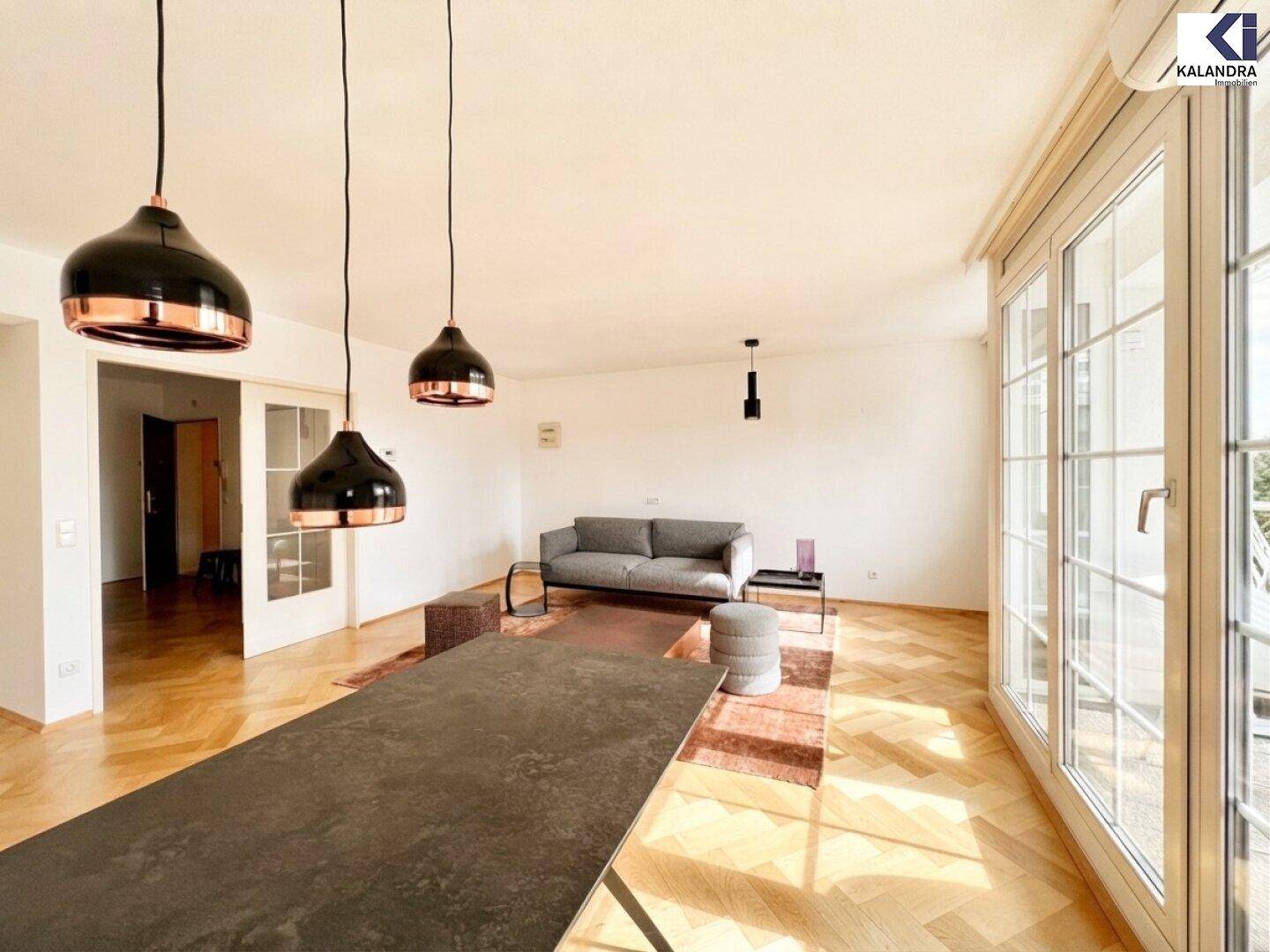 Geräumiger Wohn-Essbereich mit Parkettboden, modernem Esstisch und Zugang zum Balkon.